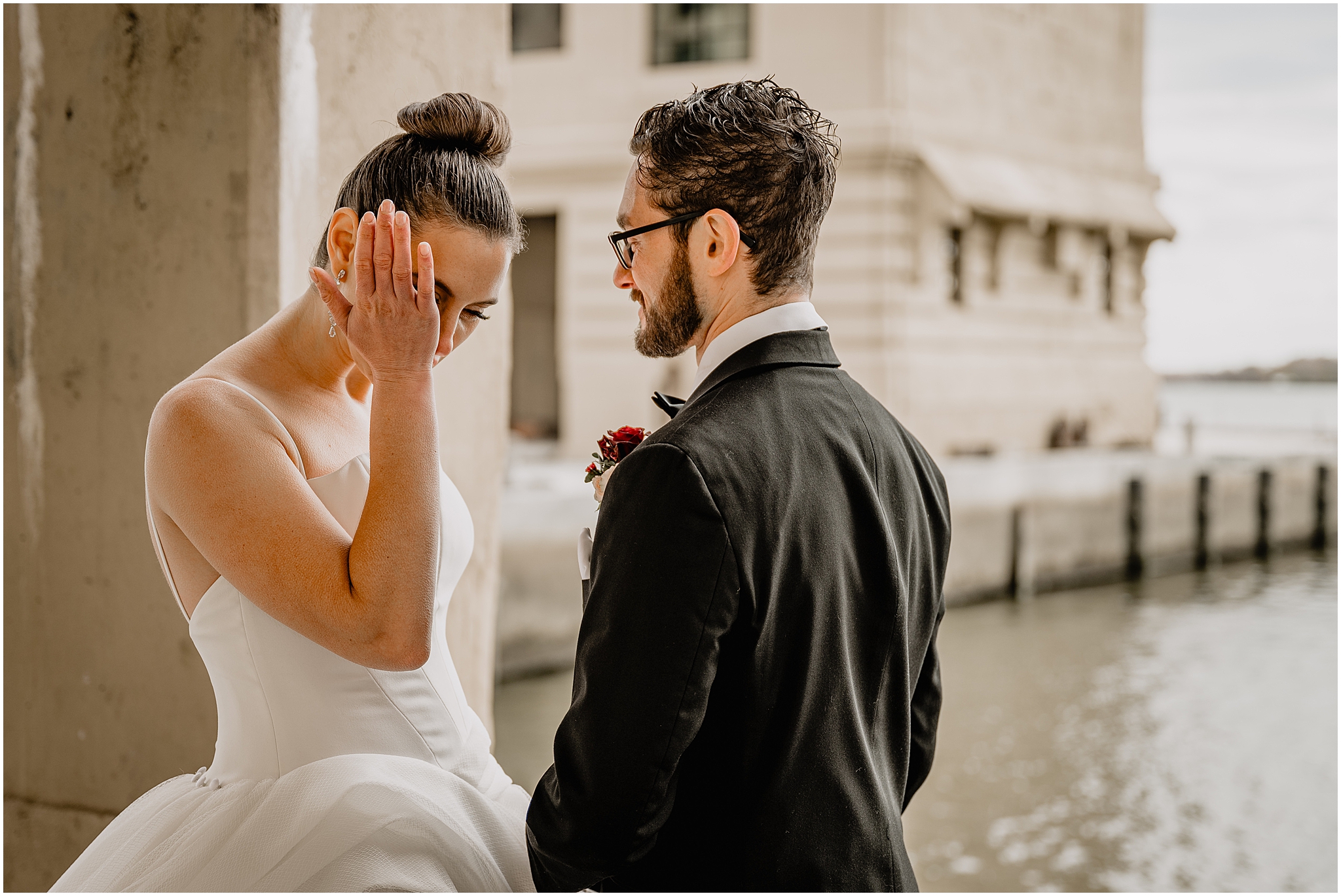 bride wipes away tears talking with groom during first look at Penn Landing along the Delaware River