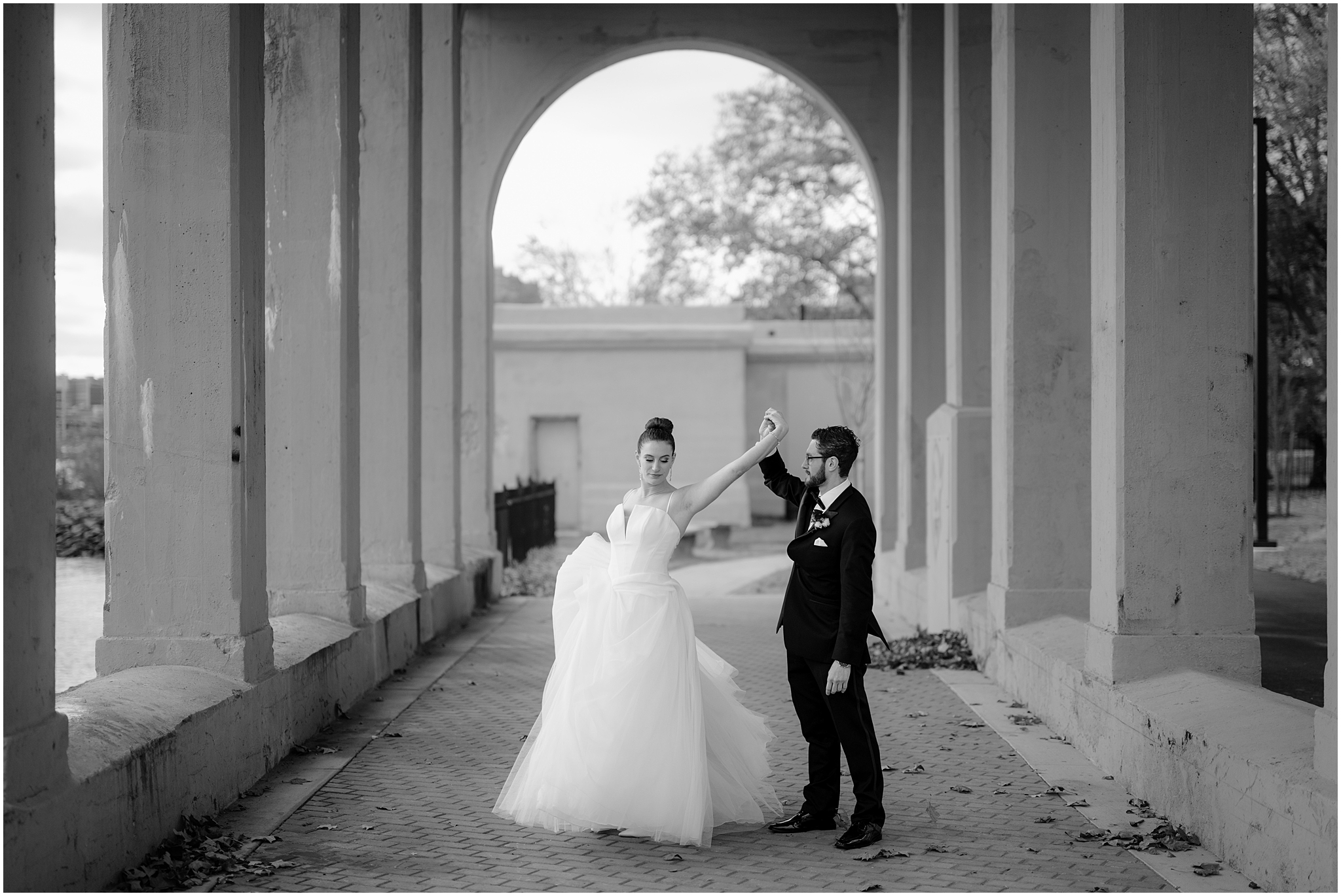 groom twirls bride under archways at Penn Landing along the Delaware River