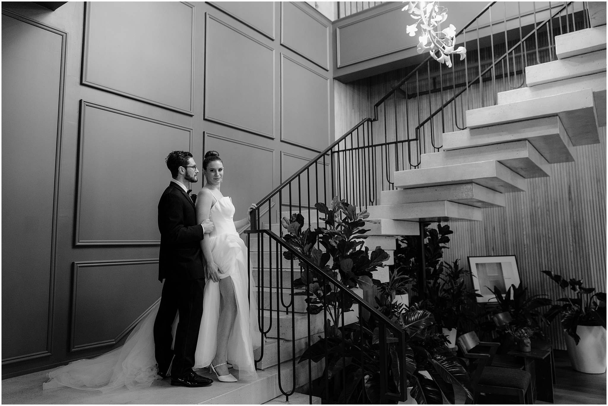 bride stands in front of groom standing on landing of staircase inside Cescaphe's Switch House
