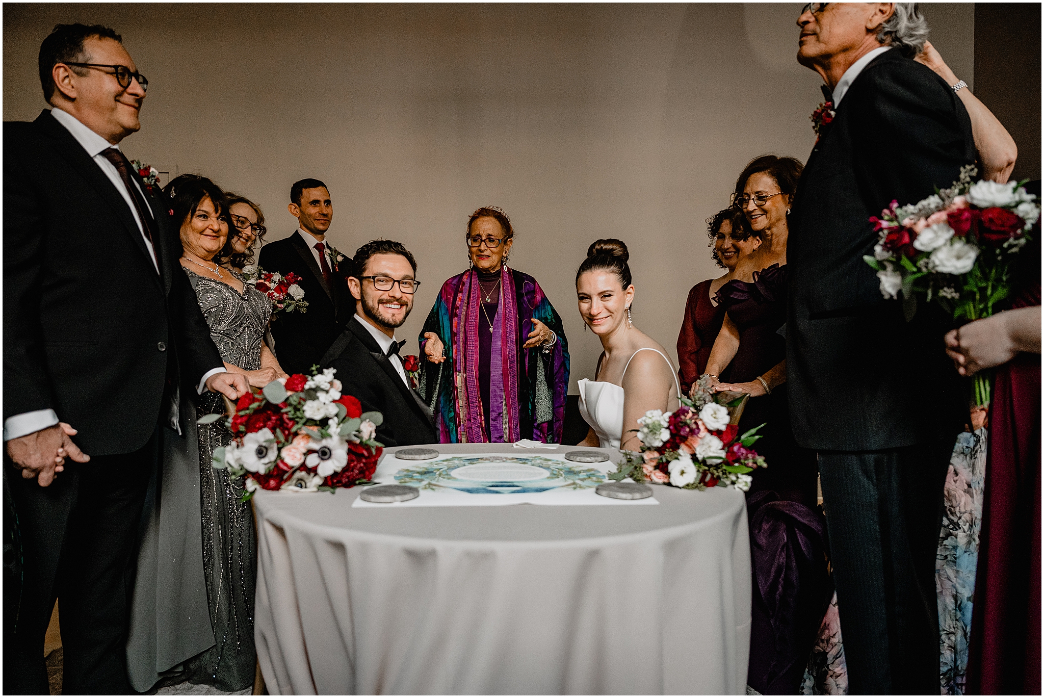 newlyweds smile sitting at table with ketubah between them on the table at Cescaphe's Switch House in Philadelphia PA