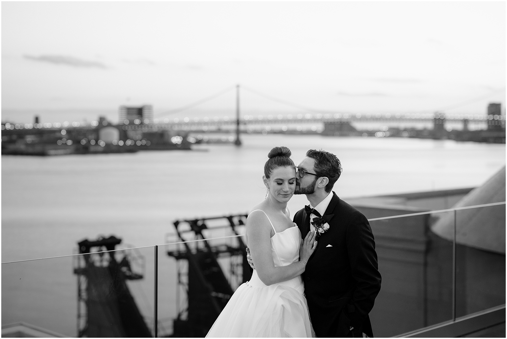 groom hugs bride around the waist kissing her cheek on the patio at Cescaphe's Switch House