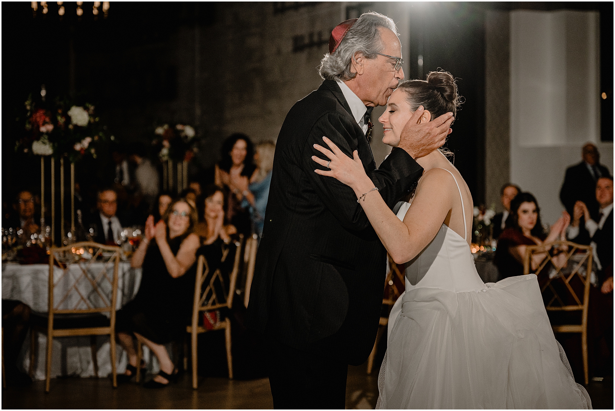 dad kisses bride's forehead during Philadelphia PA wedding reception in the ballroom