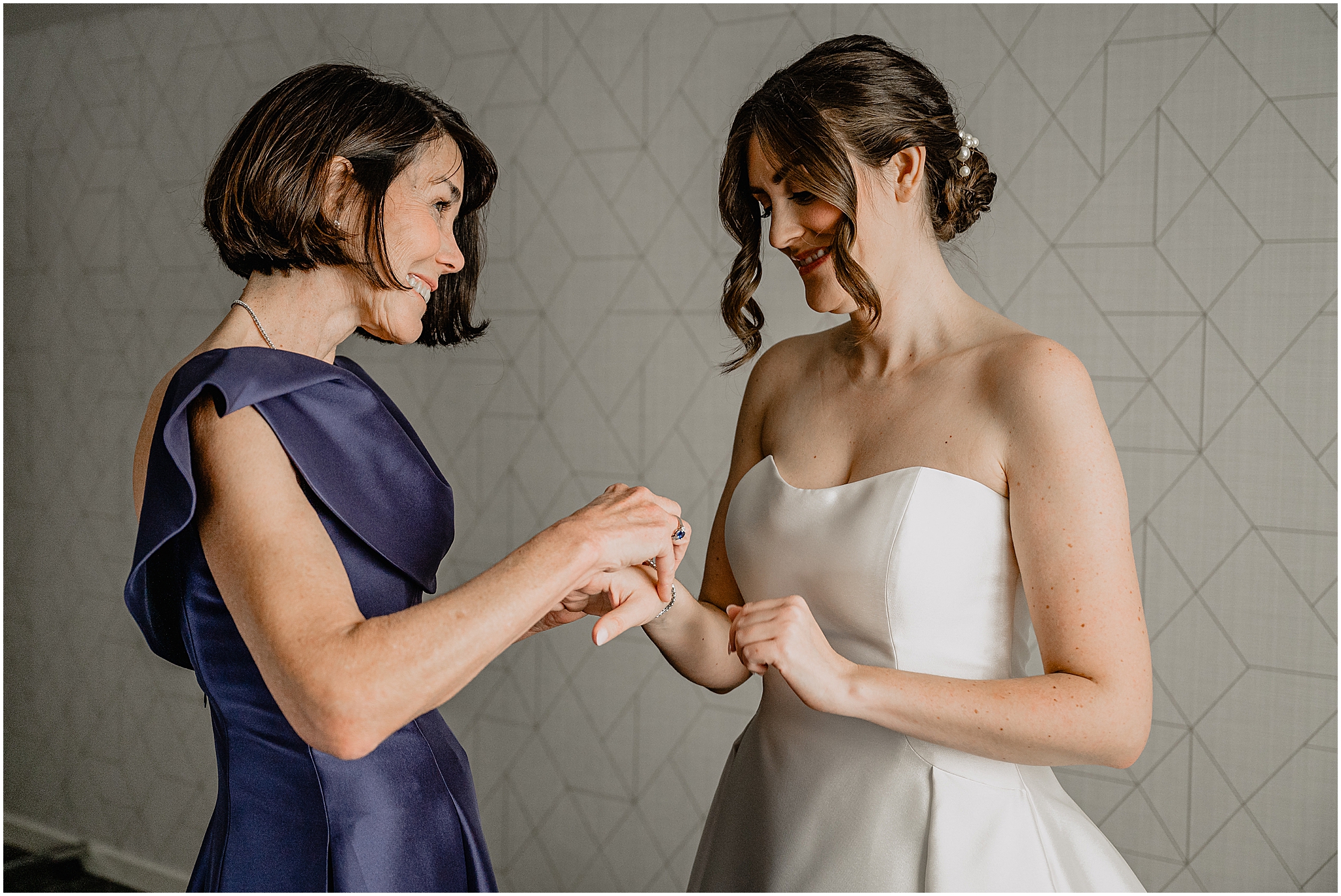mother in purple dress helps bride with bracelet during prep in Hudson Valley hotel