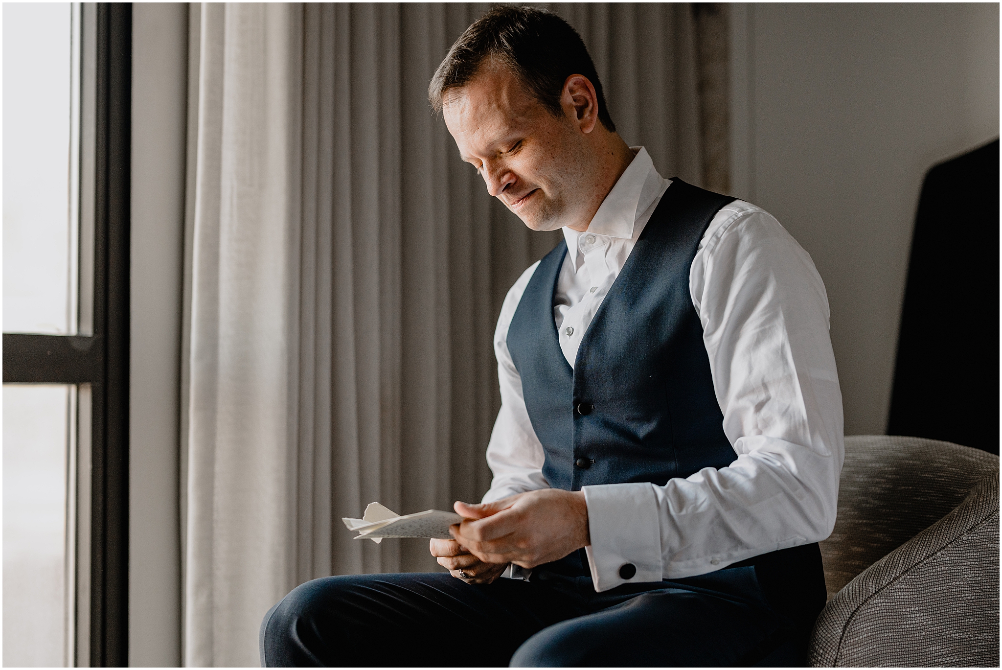 groom reads letter in hotel room during New York wedding day