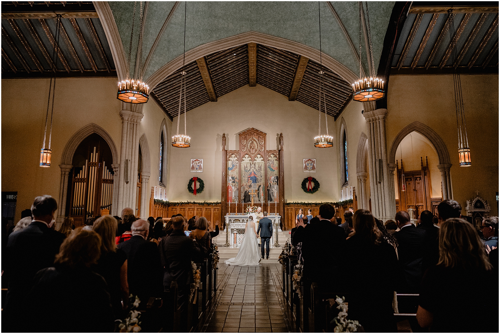 bride and groom kneel in front of alter during traditional Catholic wedding ceremony inside New York Church