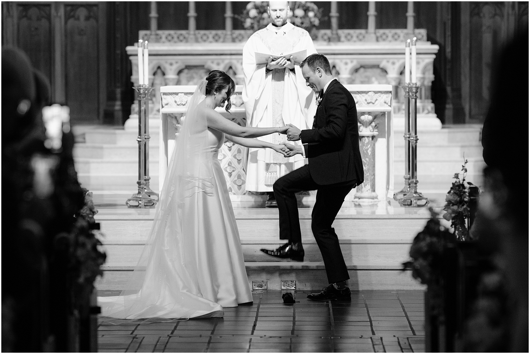 bride and groom hold hands during traditional Catholic wedding ceremony inside New York Church