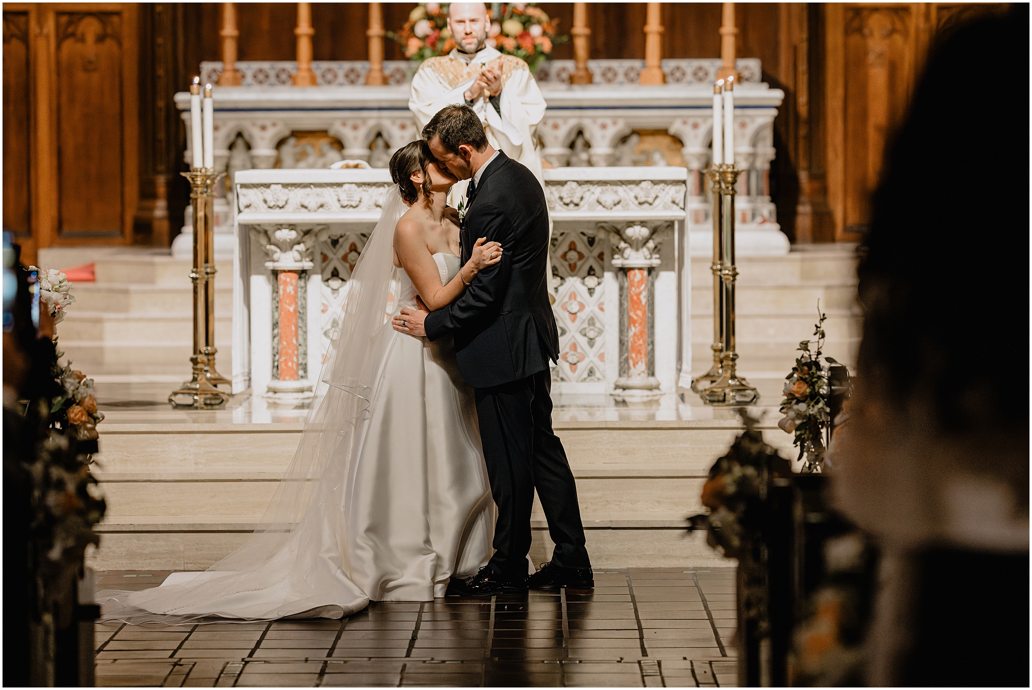 newlyweds kiss during traditional Catholic wedding ceremony inside New York Church