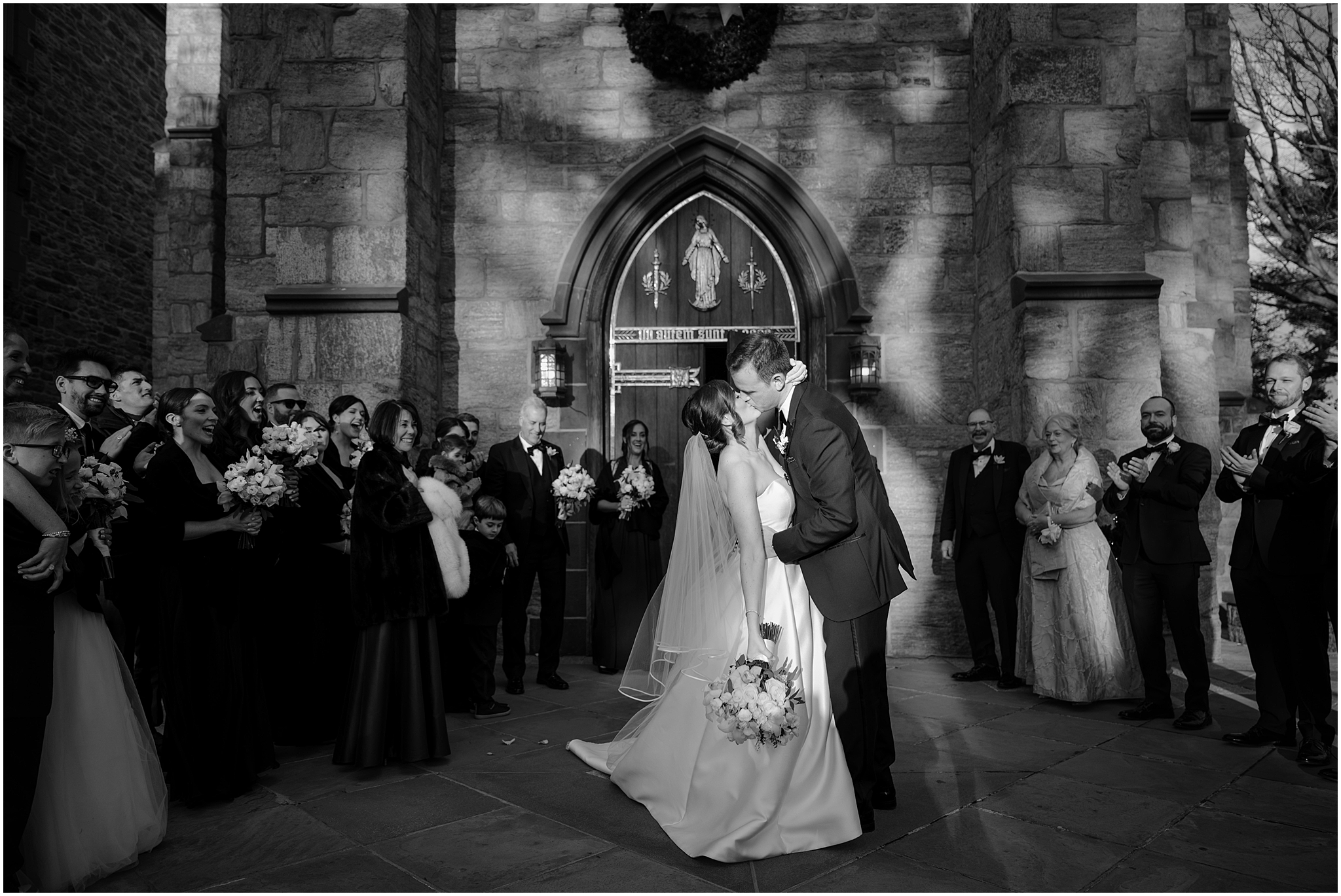 bride and groom kiss outside stone church in New York after ceremony 