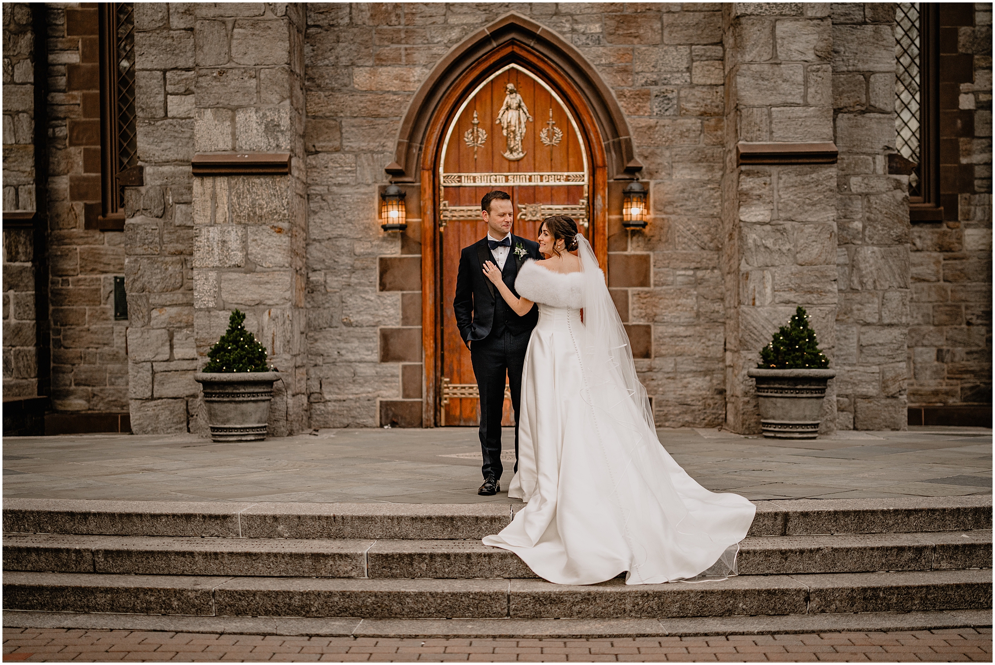 bride and groom stand on steps of New York church during wedding portraits in the Hudson Valley