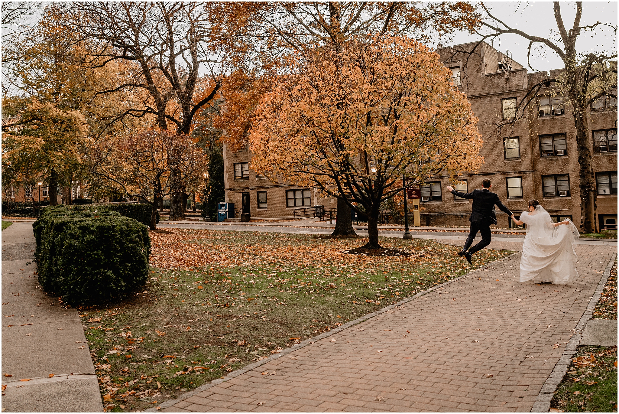 groom jumps clicking his heels together walking down street outside church in the Hudson Valley