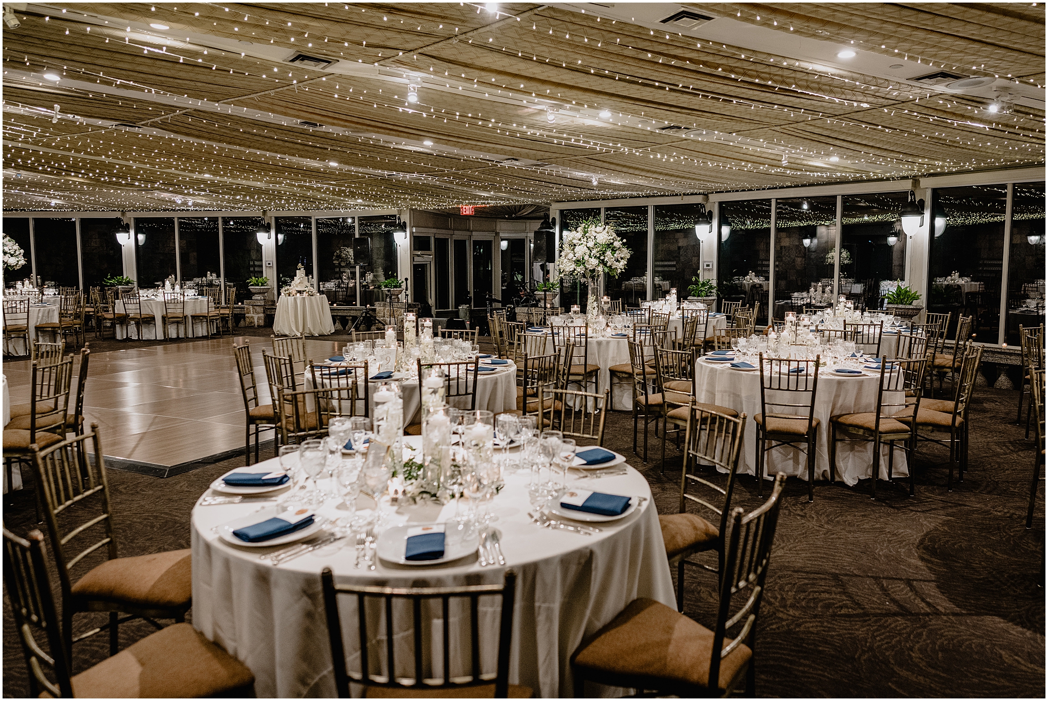 wedding reception inside the ballroom at Tappan Hill Mansion with twinkling lights, blue napkins, and white plates