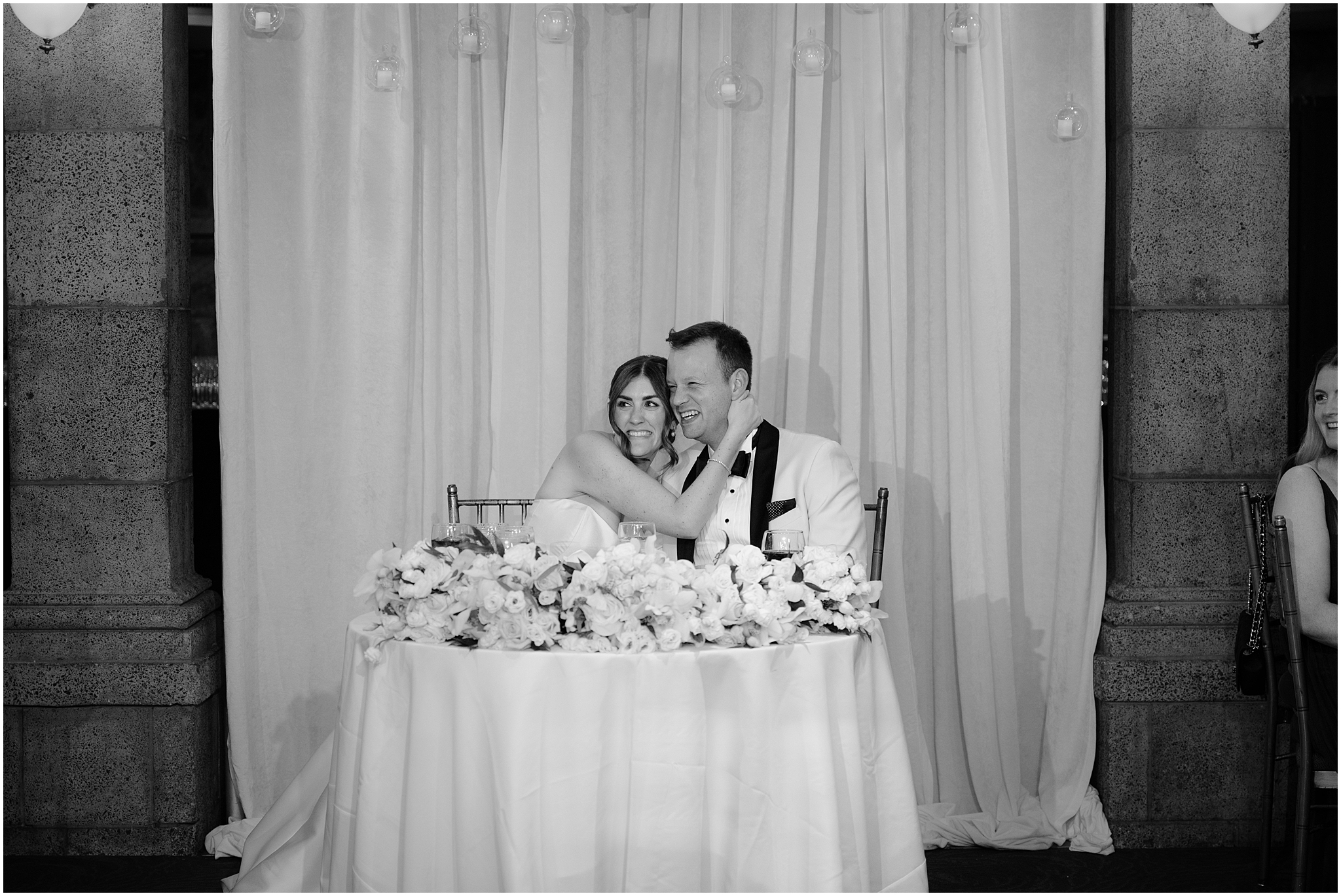bride hugs groom sitting close at their sweetheart table during Tarrytown NY wedding reception