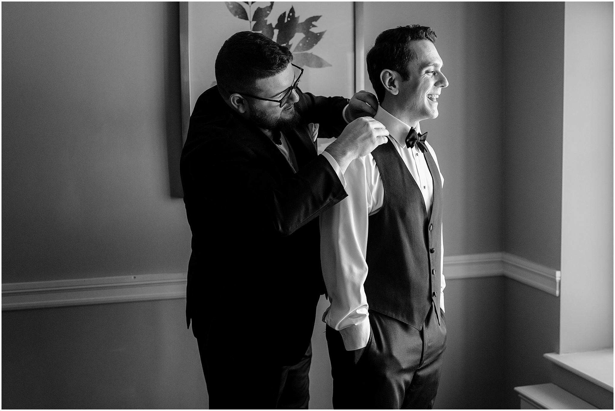 groomsman helps groom adjust bowtie during prep in Madison Hotel