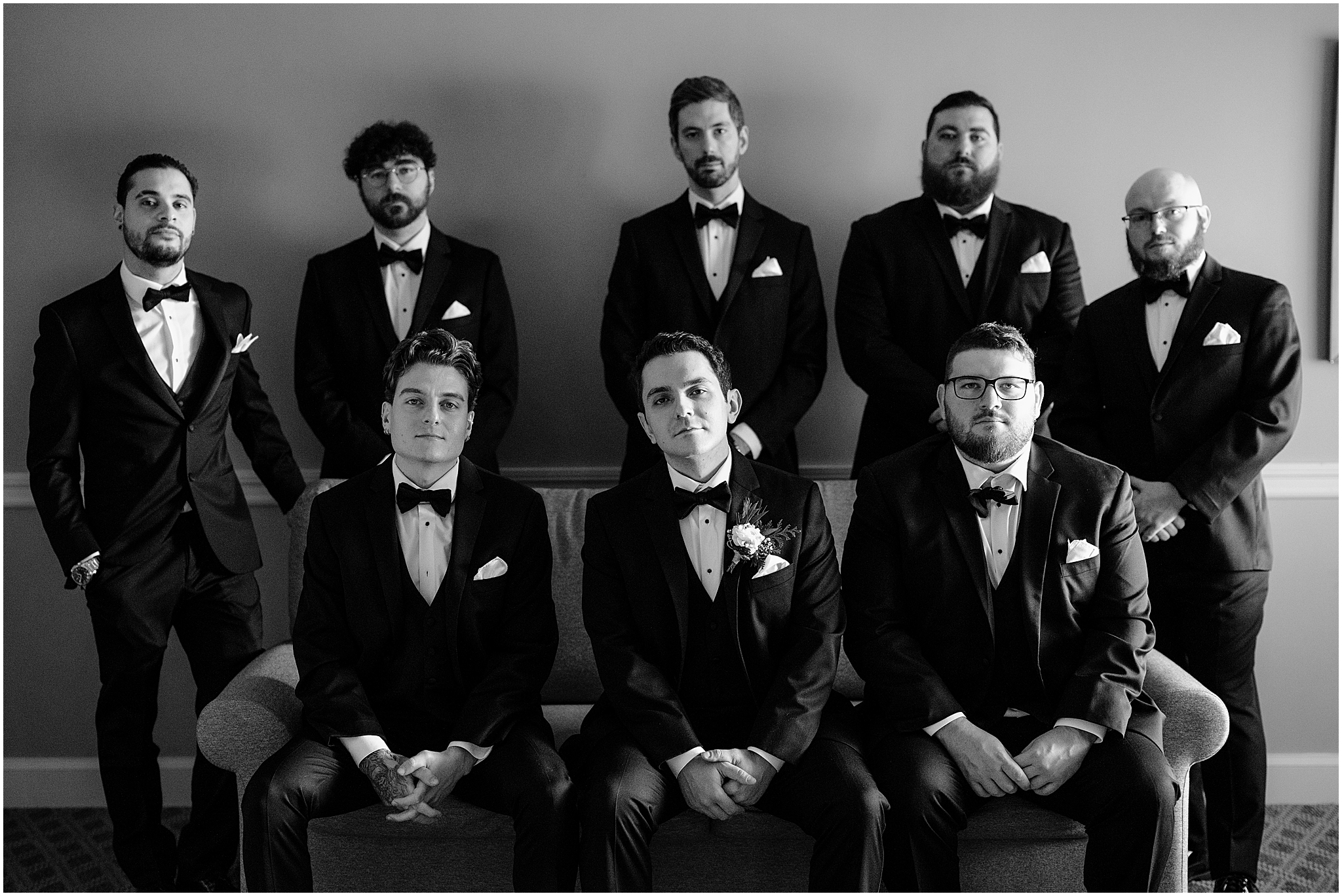 groom sits with groomsmen on sofa inside the Madison Hotel in Morristown NJ