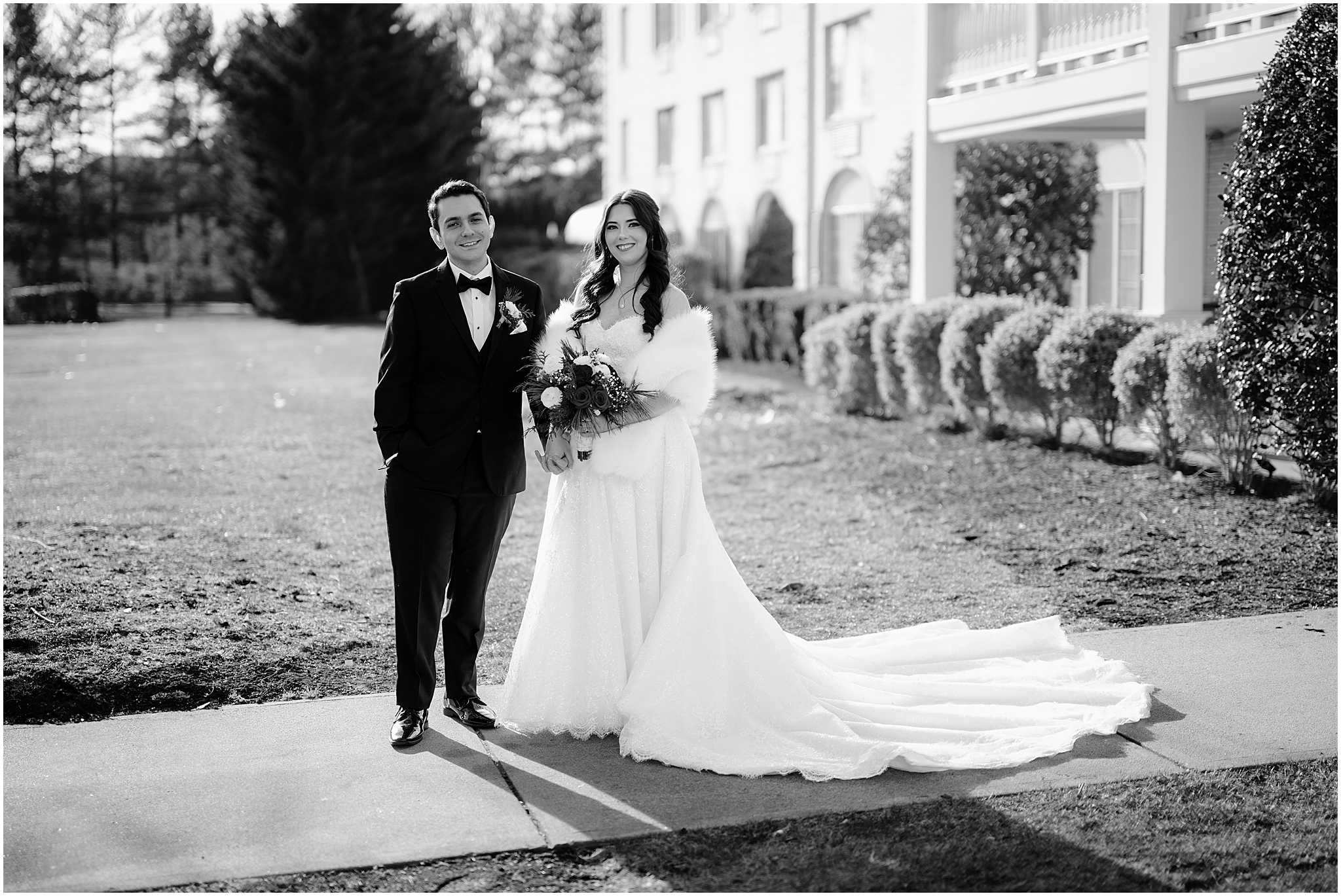 bride with dress and white fur stands next to groom outside the Madison Hotel in Morristown NJ
