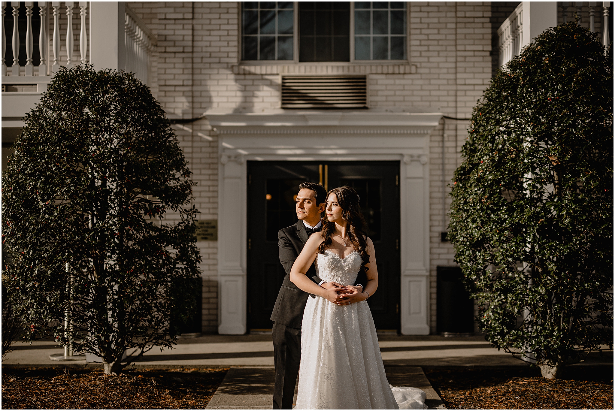 groom hugs bride from behind outside the Madison Hotel in Morristown NJ
