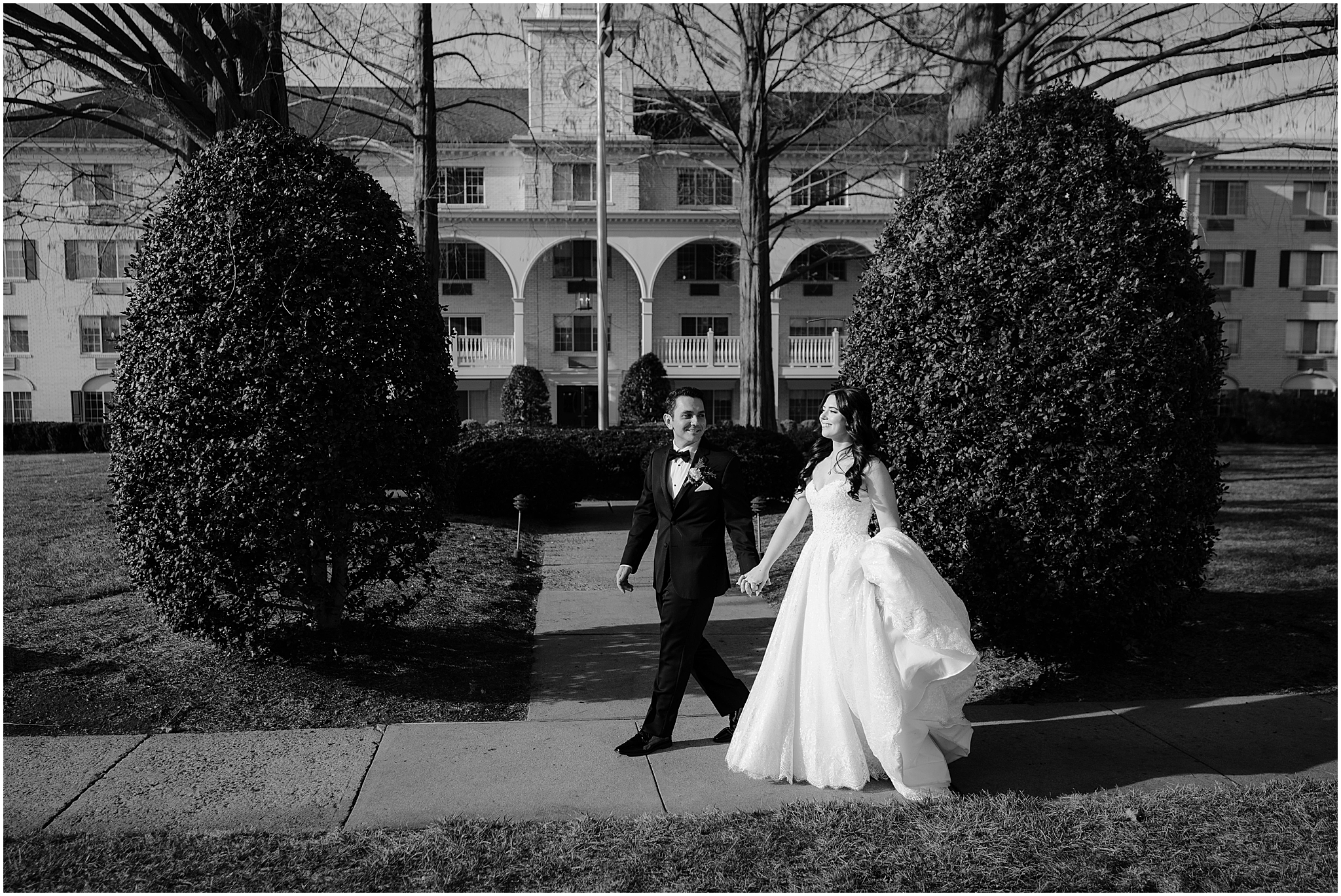 bride and groom hold hands walking down sidewalk outside the Madison Hotel in Morristown NJ