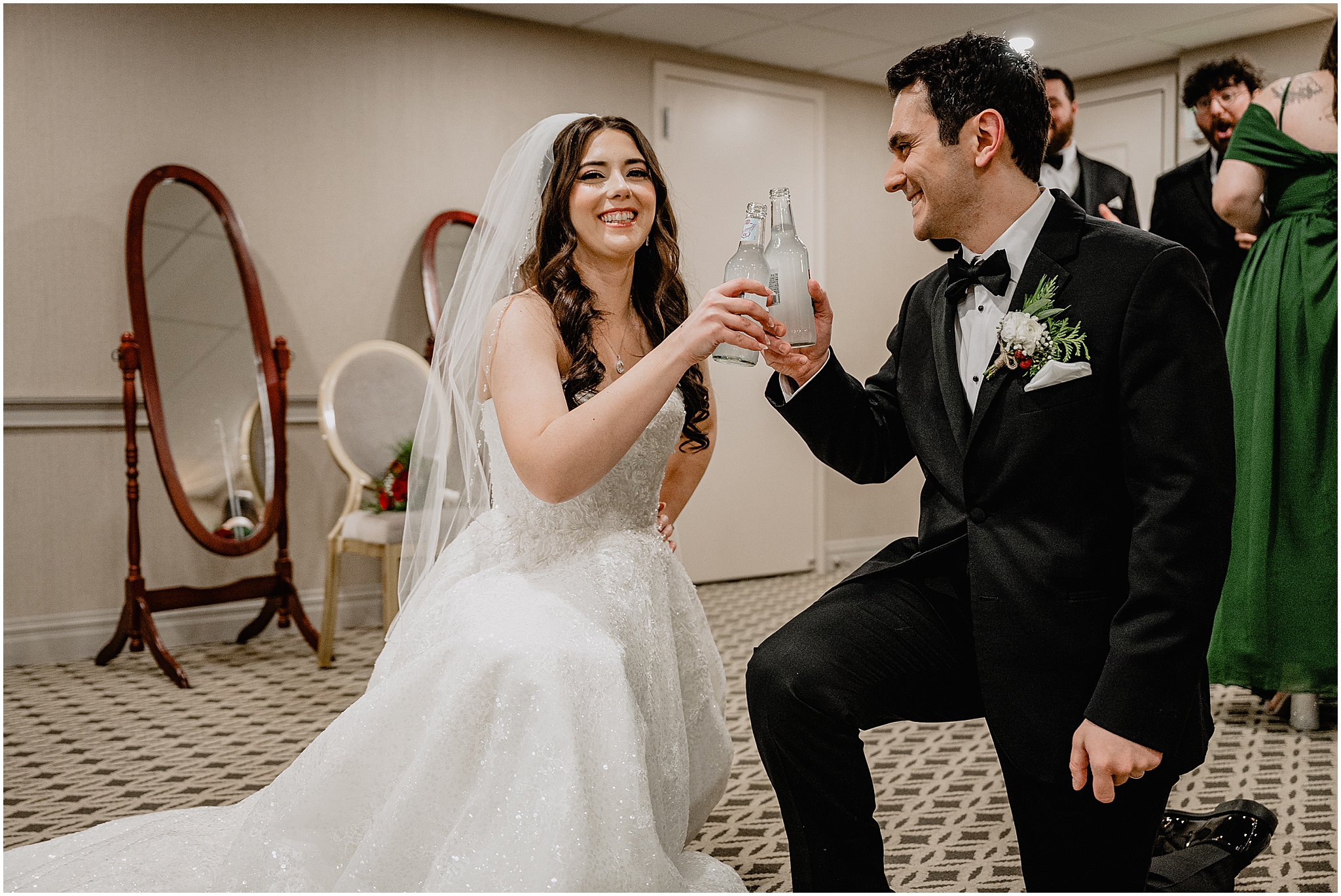 bride and groom kneel drinking Smirnoff ice inside hotel