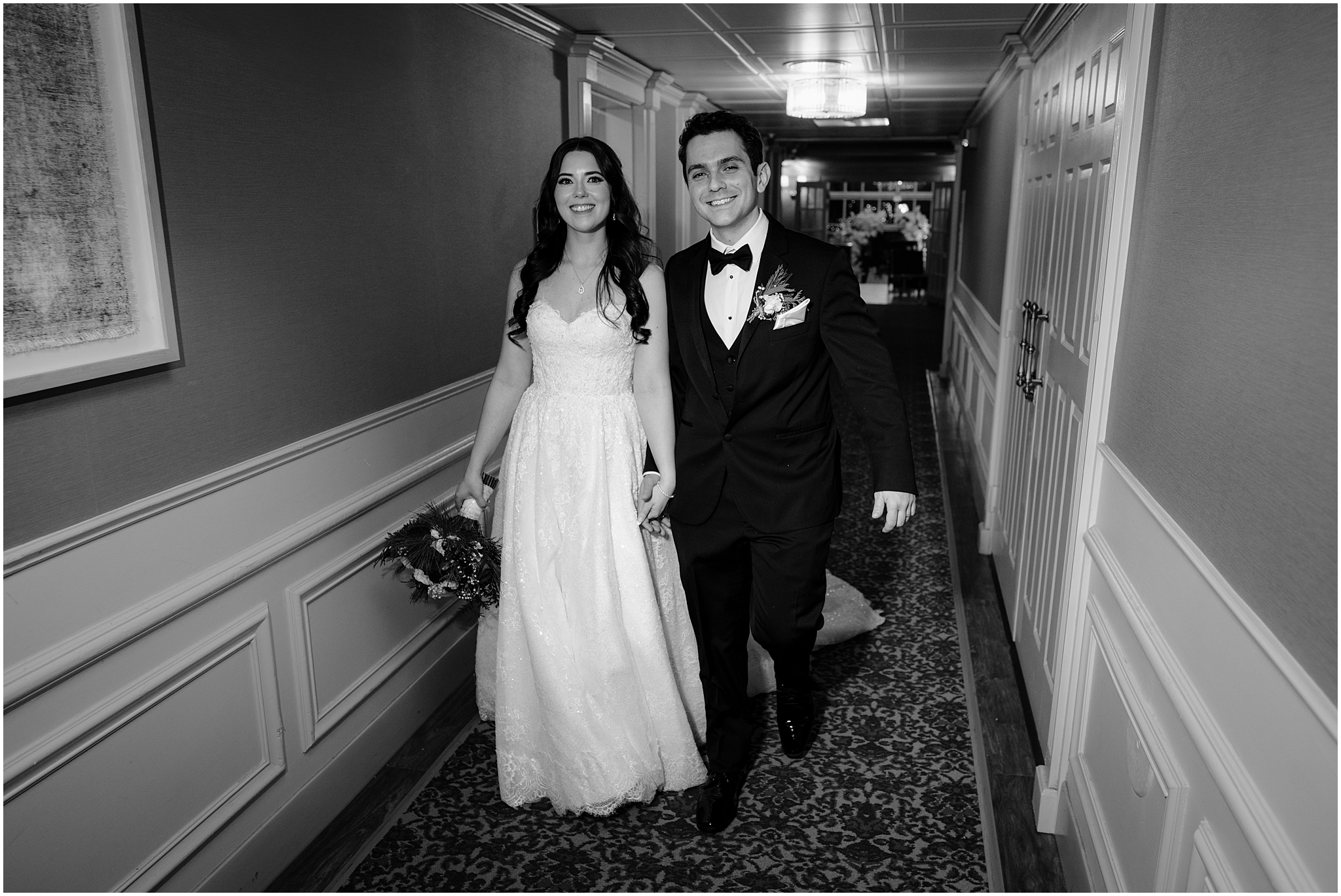 newlyweds walk through hallway at the Madison Hotel holding hands