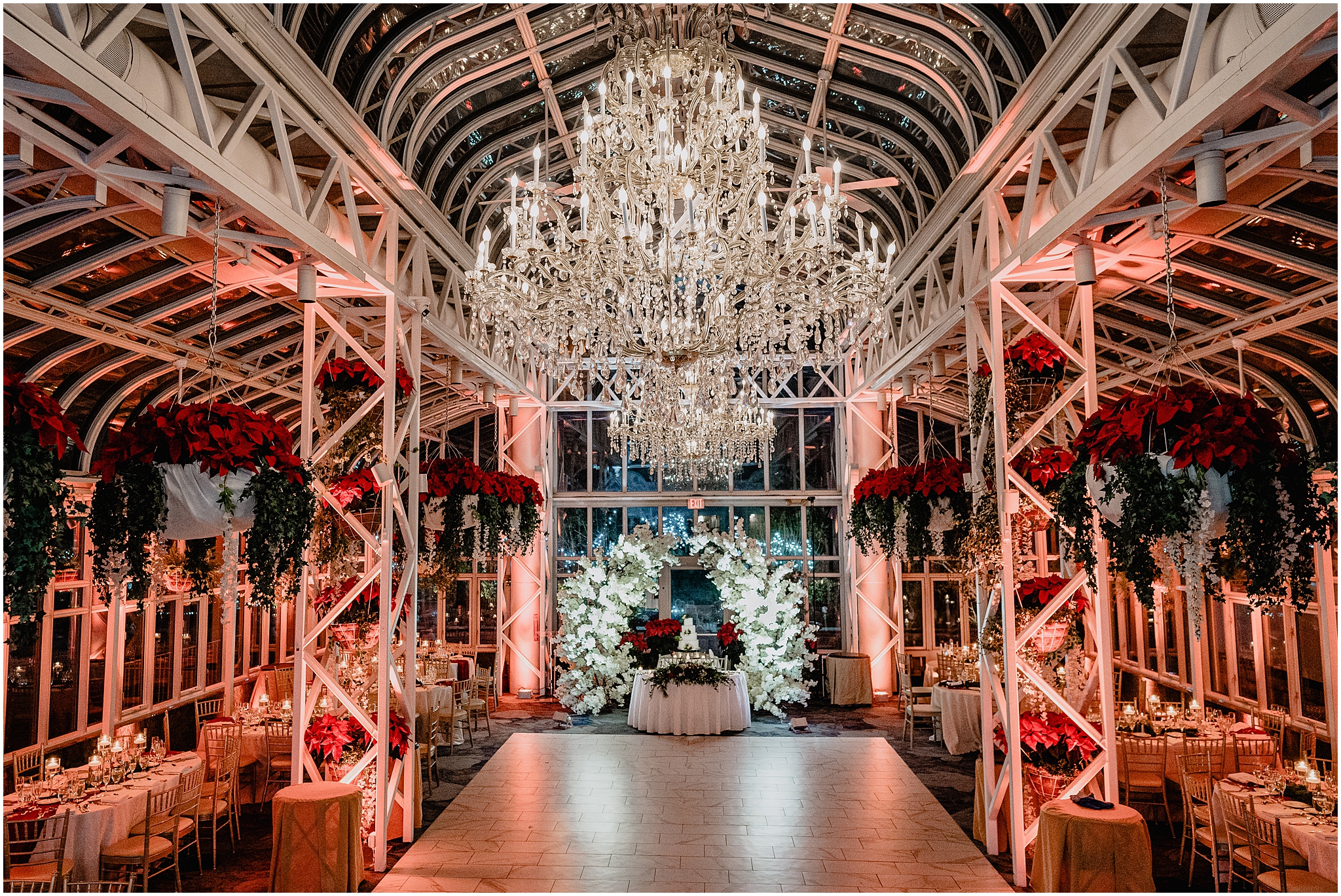 wedding reception inside the atrium at the Madison Hotel with red poinsettias and cake display at the end of the dance floor