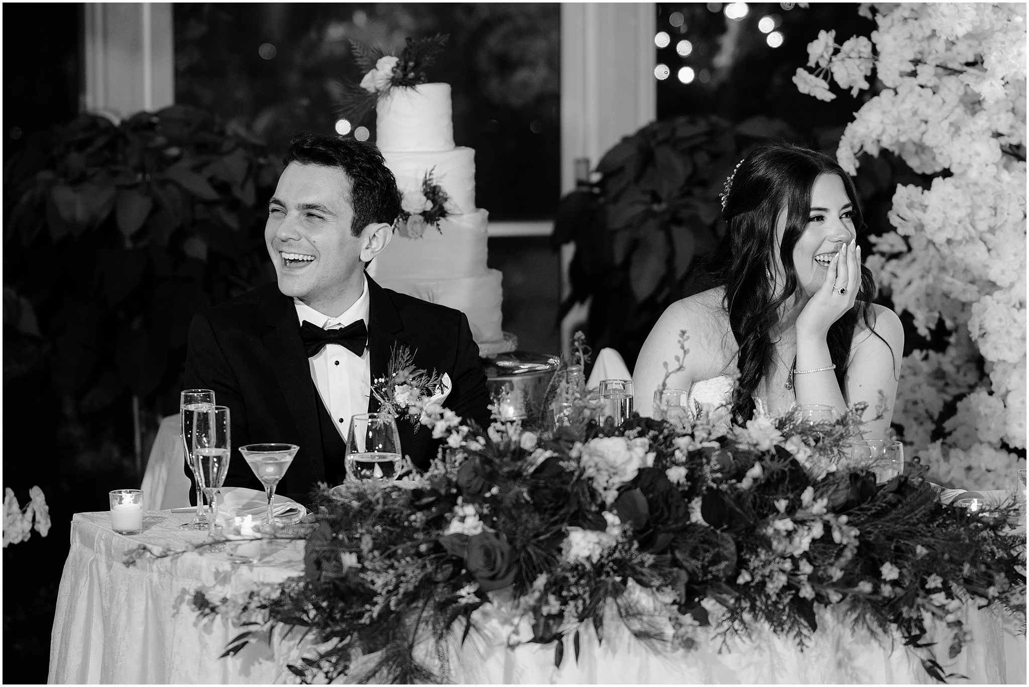 bride and groom laugh sitting at sweetheart table during wedding reception in Morristown NJ