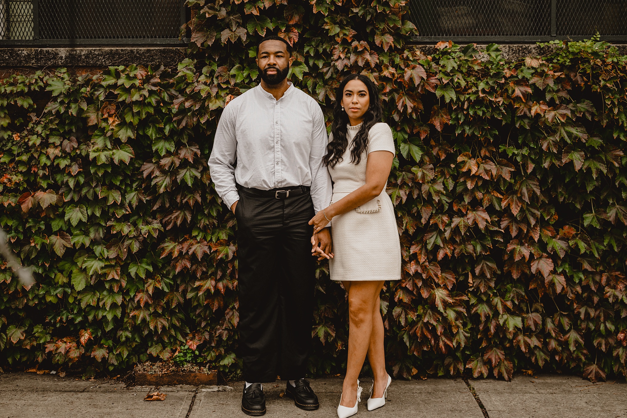 woman in white dress holds man's hand outside The Foundry on their Long Island Engagement Session
