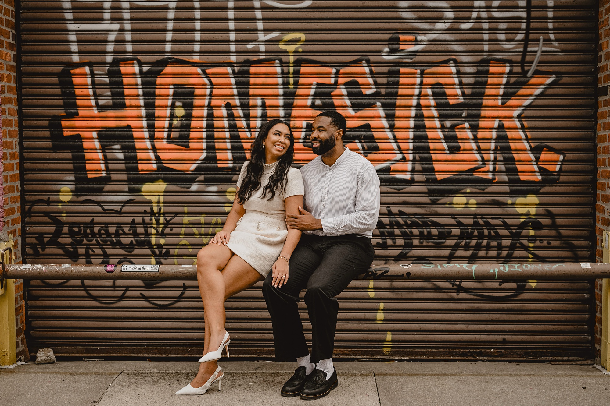 couple sits in front of graffiti mural for their Long Island Engagement Session