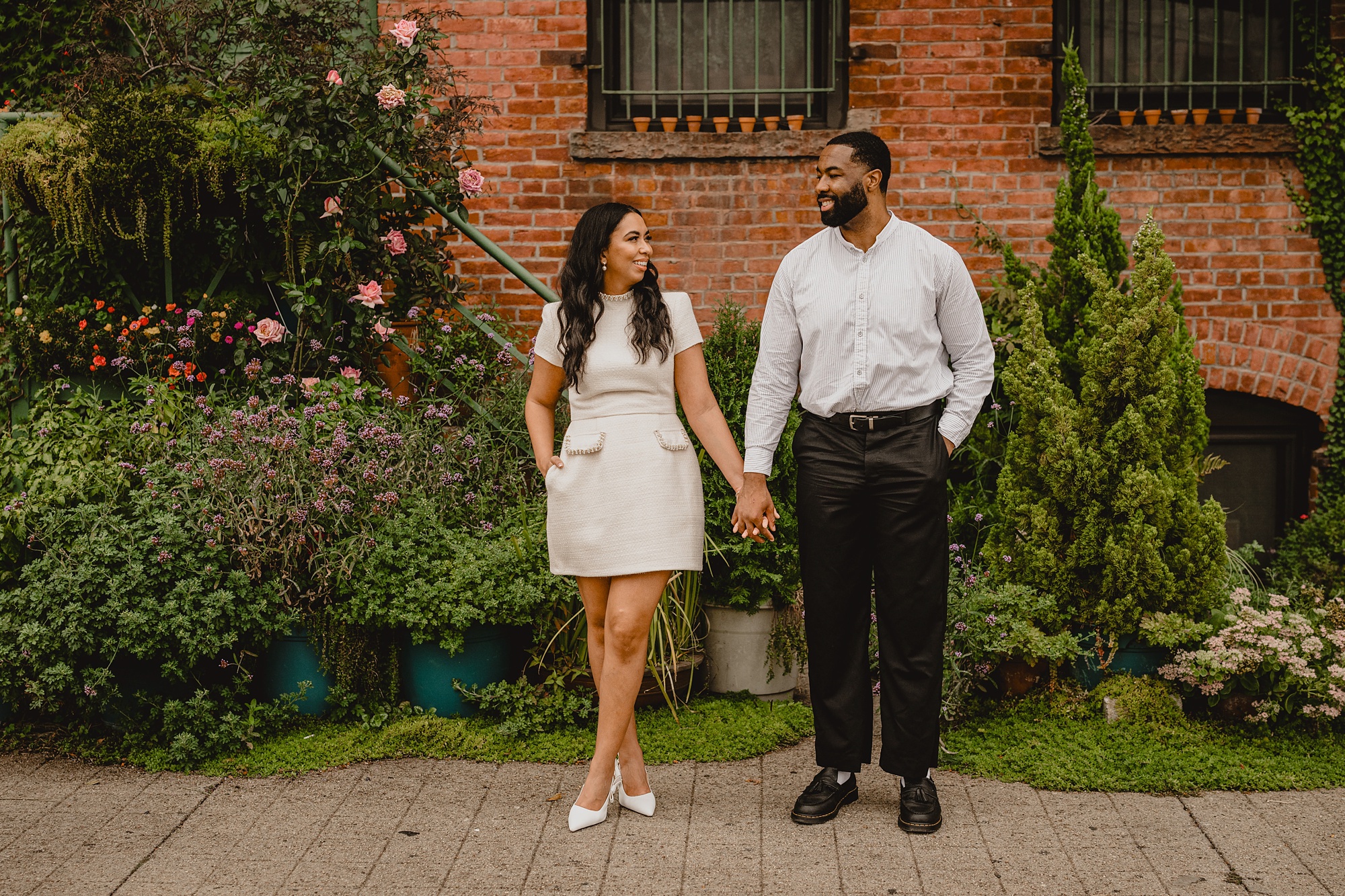 man and woman hold hands standing outside urban garden on their Long Island Engagement Session