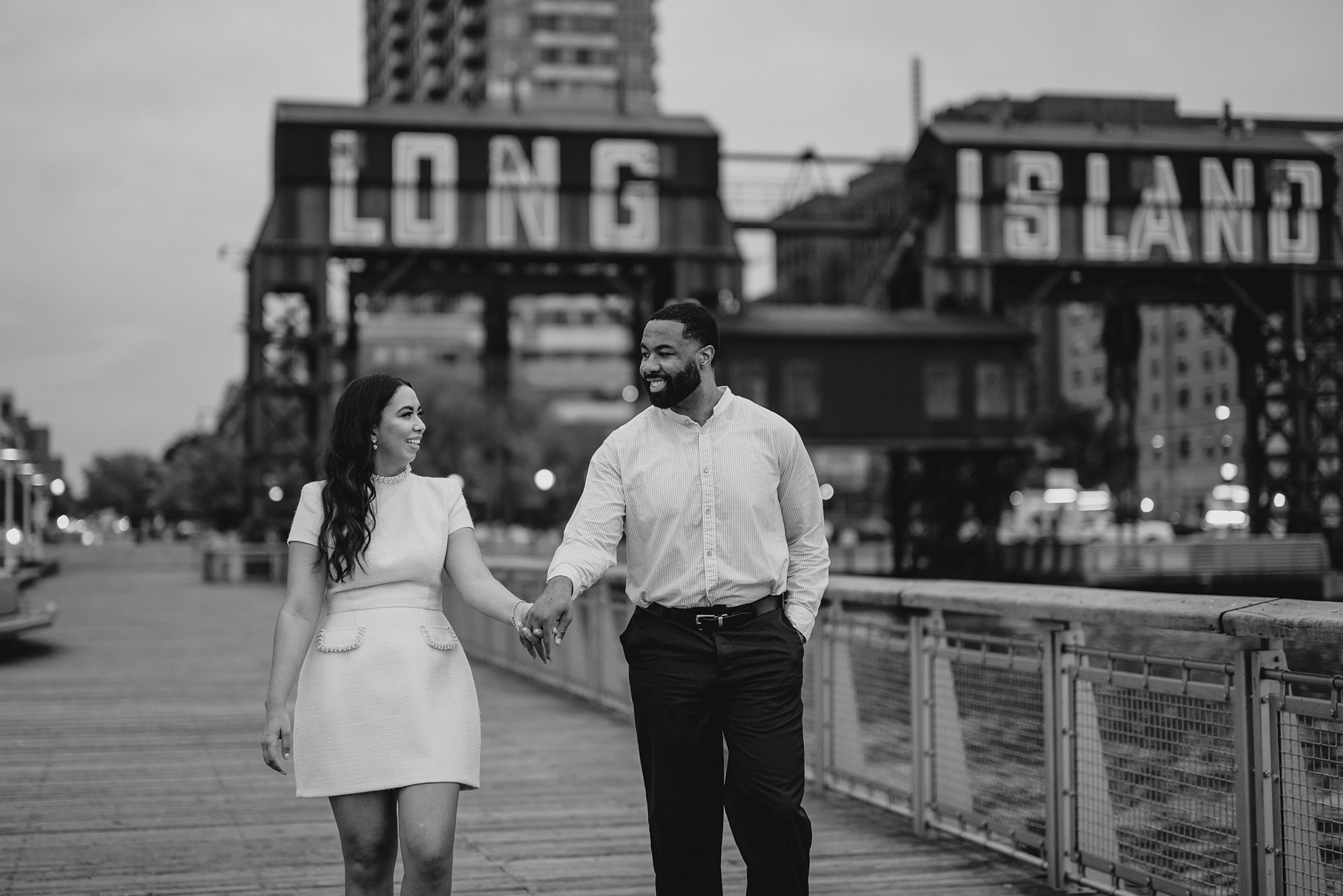 couple hugs in front of Long Island City buildings at Gantry State Park Plaza