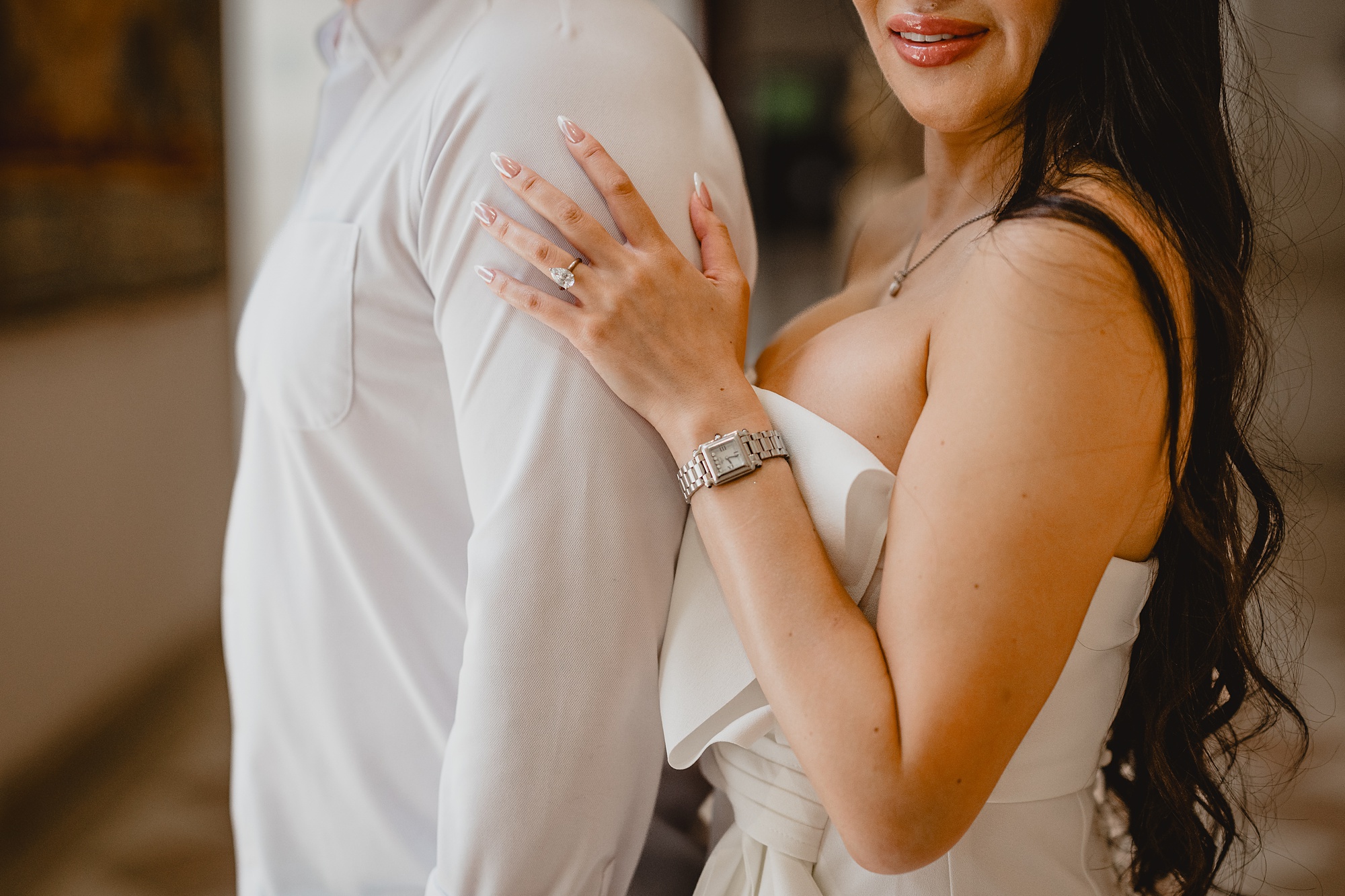 woman holds man's arm showing off engagement ring and watch