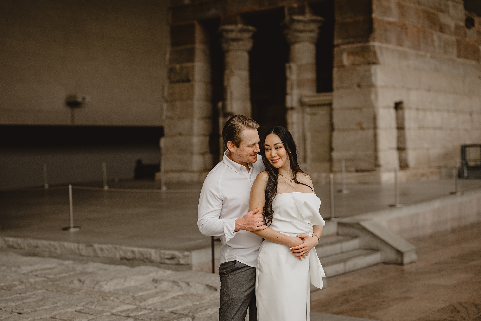 man hugs woman from behind during the Met Museum engagement session