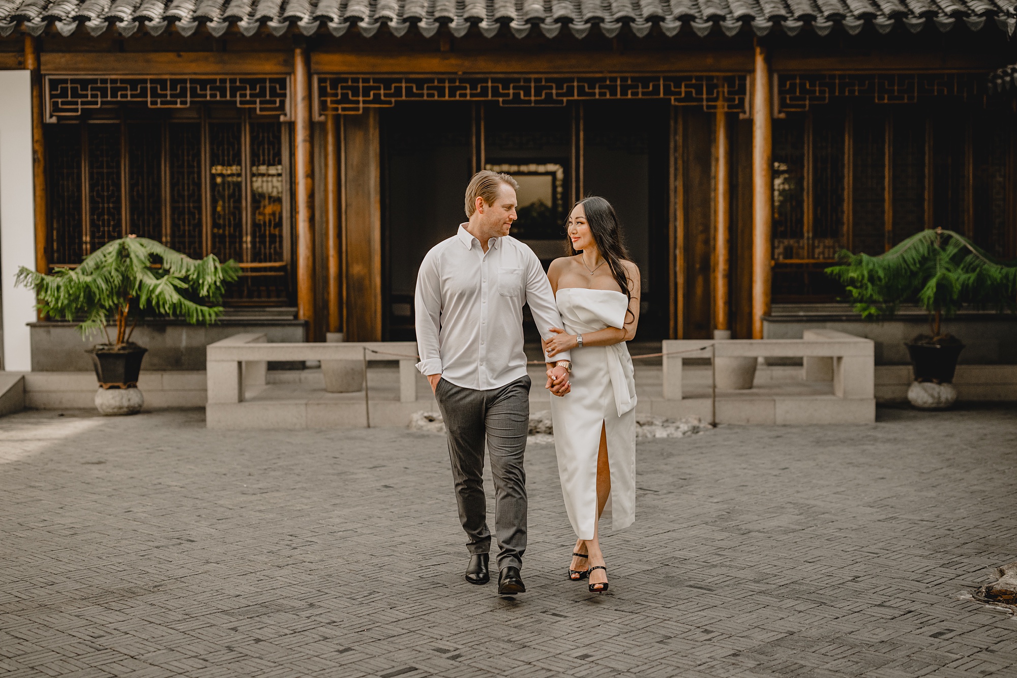 man and woman walk outside Asian inspired building 