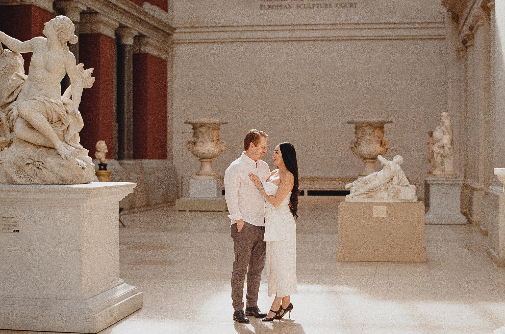 couple hugs between statues photographed on film 