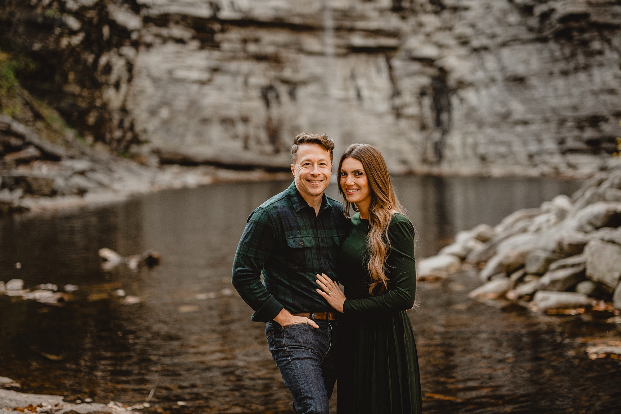 woman hugs man laying her hand on his chest in front of rock structure during their Lake Minnewaska Engagement Session