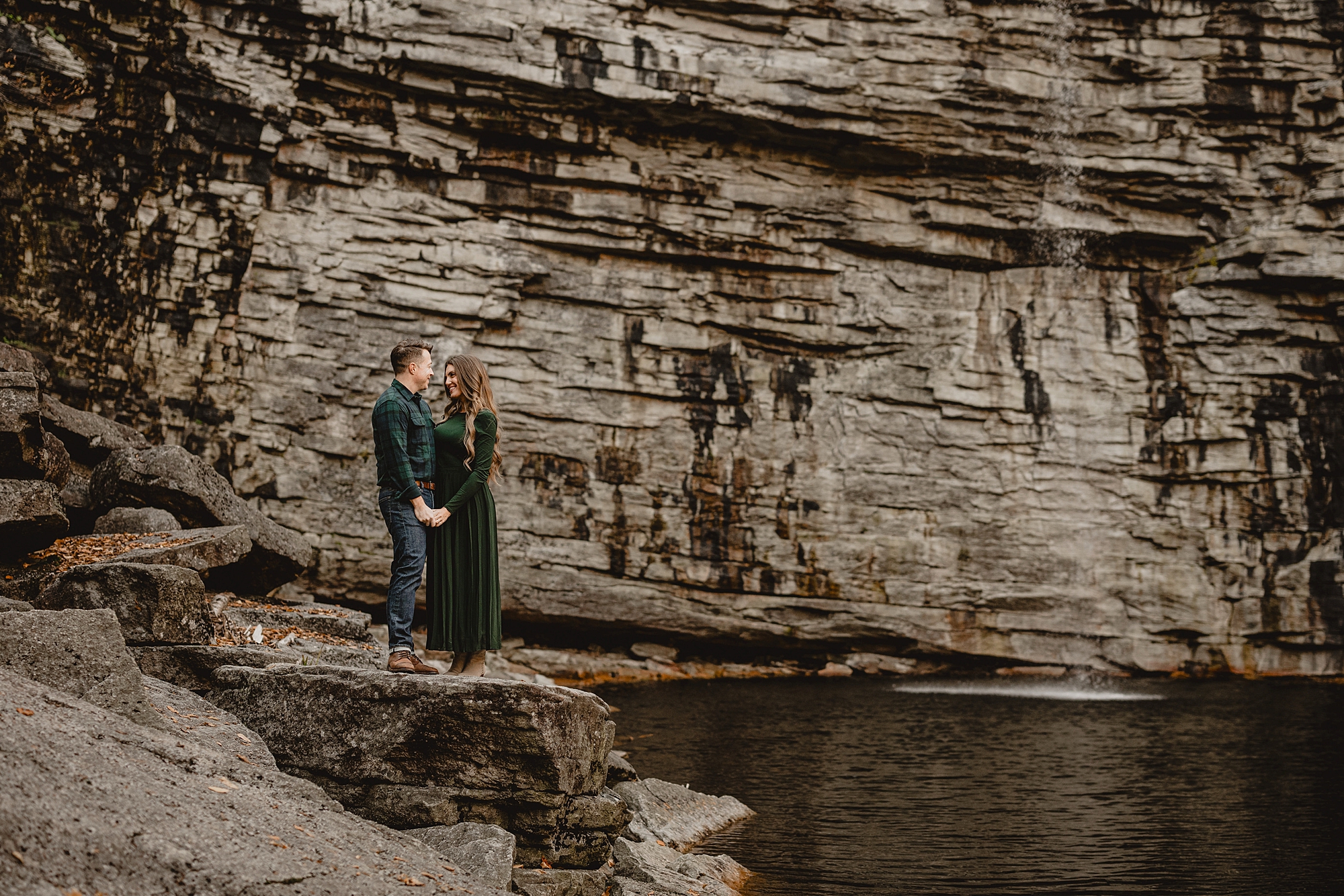 woman in green dress leads man along edge of Lake Minnewaska