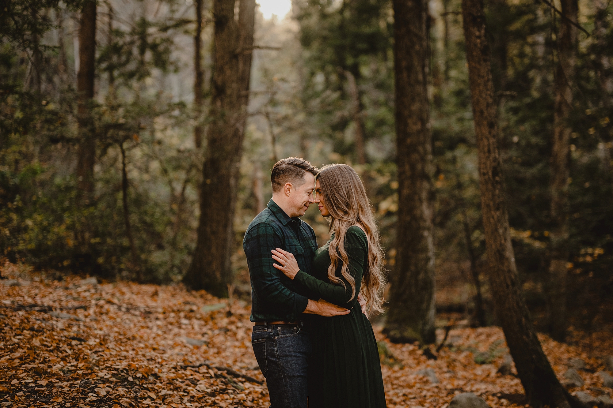 man and woman hug in front of trees around Lake Minnewaska