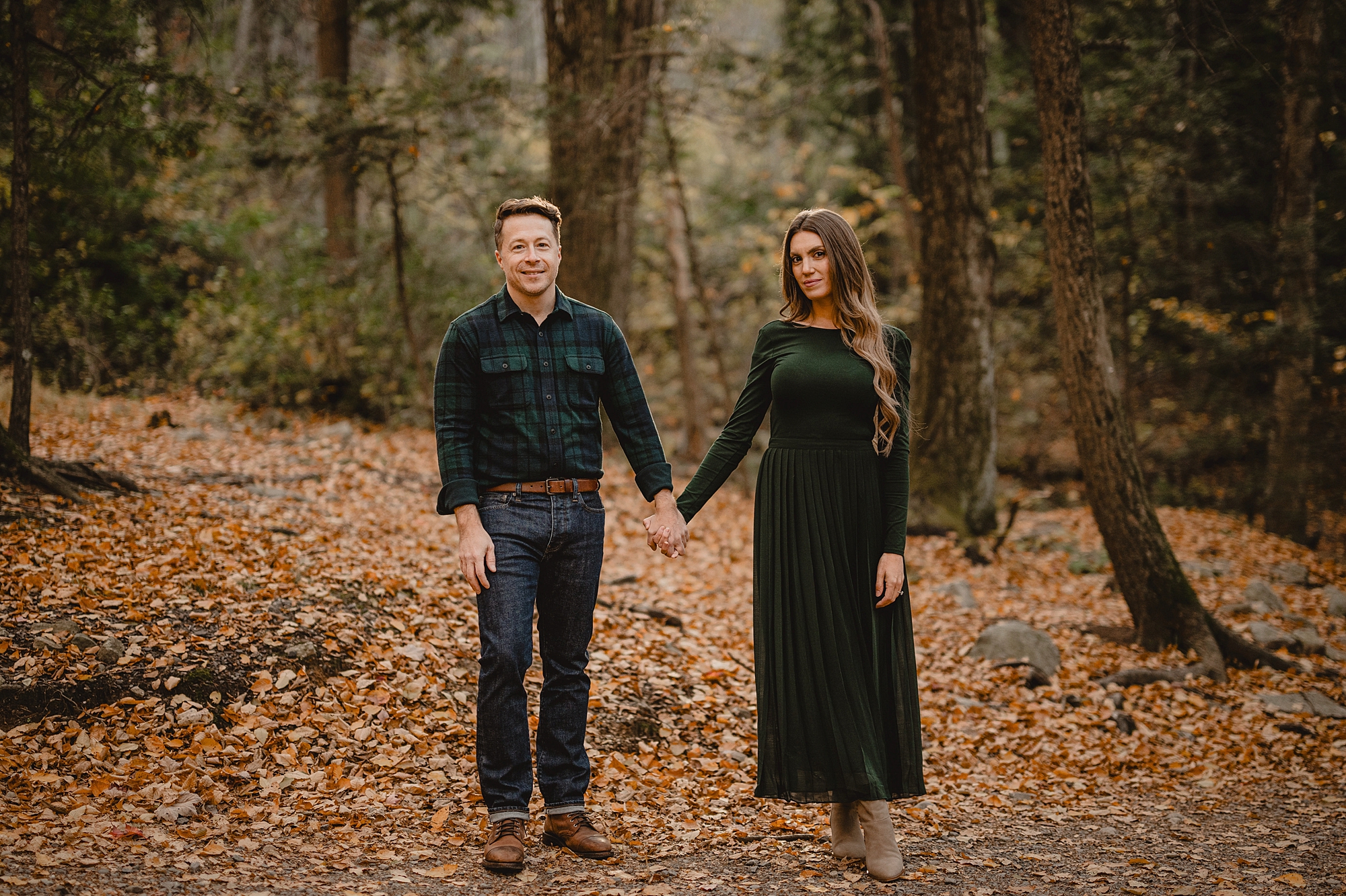 man and woman hold hands standing on leaf covered path in Hudson Valley NY