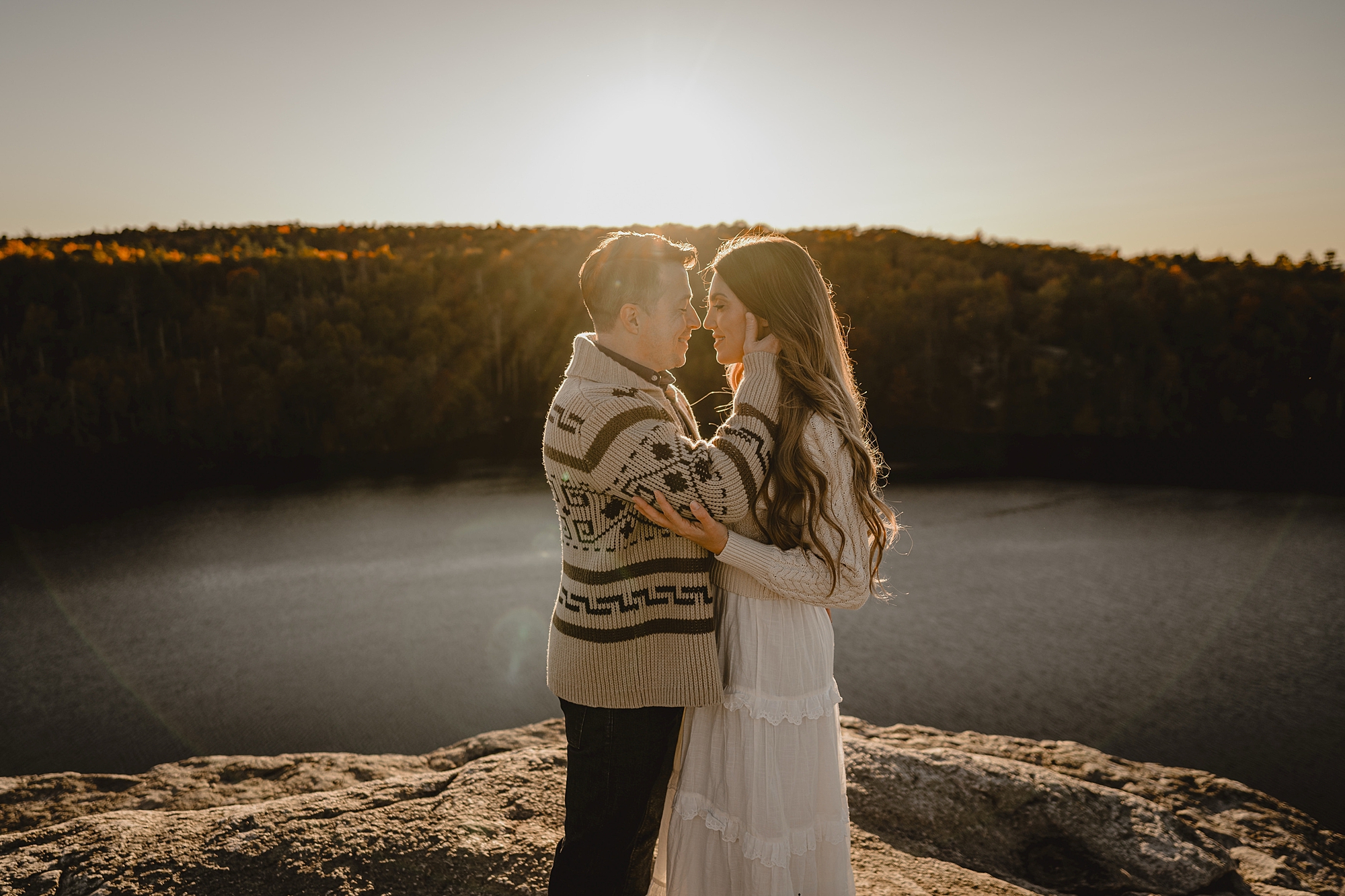 man and woman hug as sun sets behind them at Lake Minnewaska