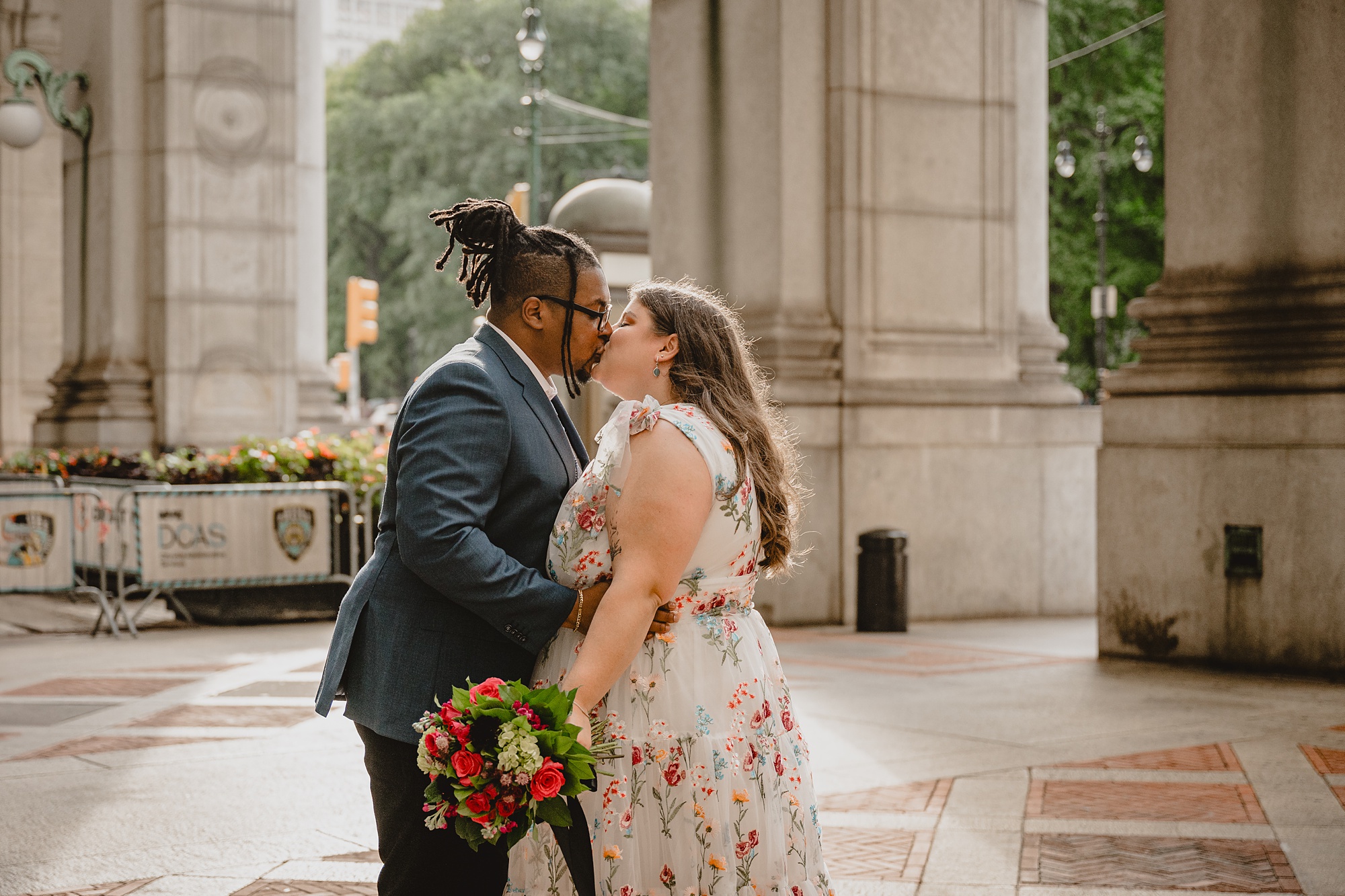 bride and groom kiss in front of pillars at NYC City Hall