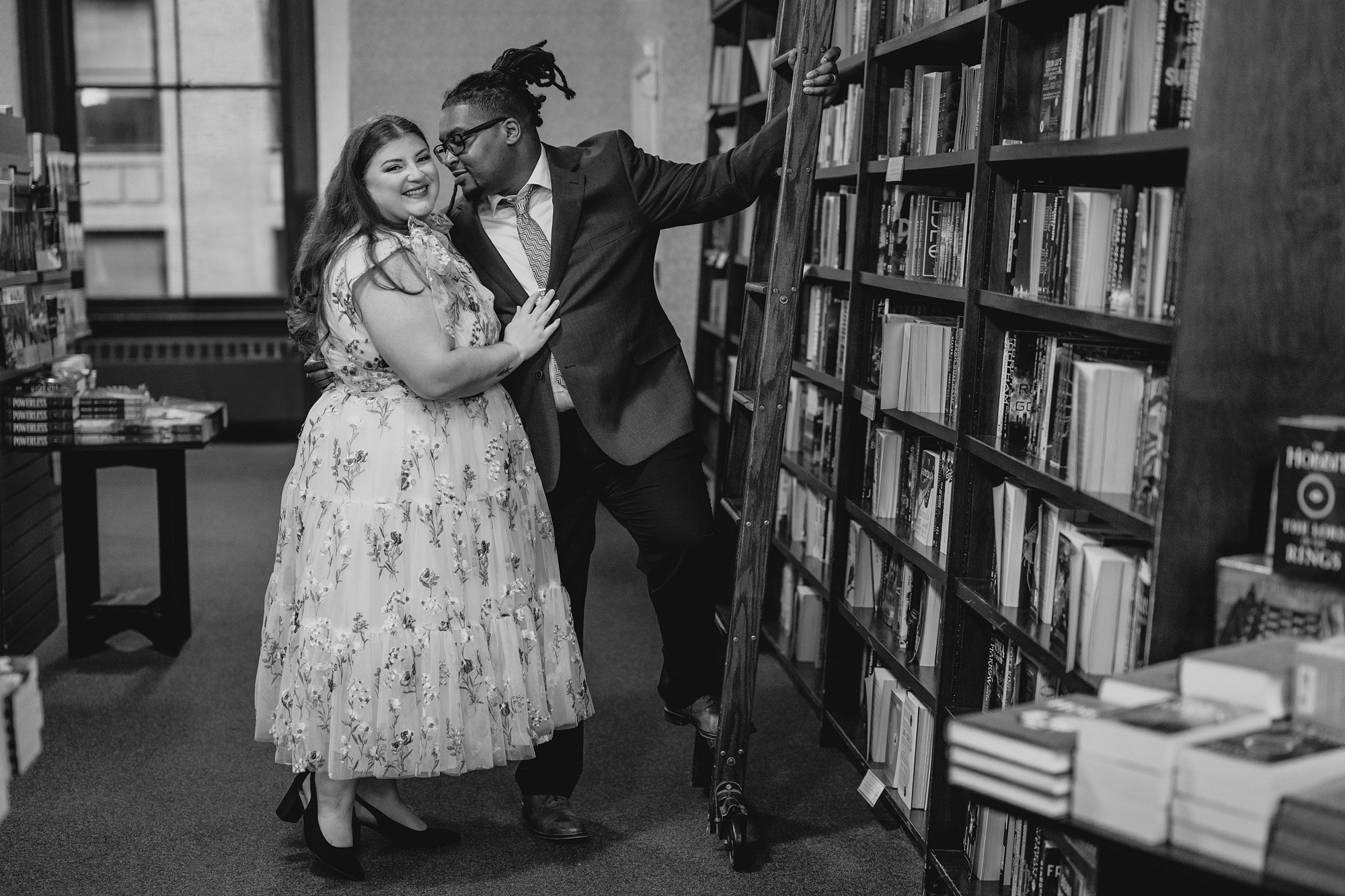 man leans to kiss woman's cheek in row of books at Barnes & Noble in NYC