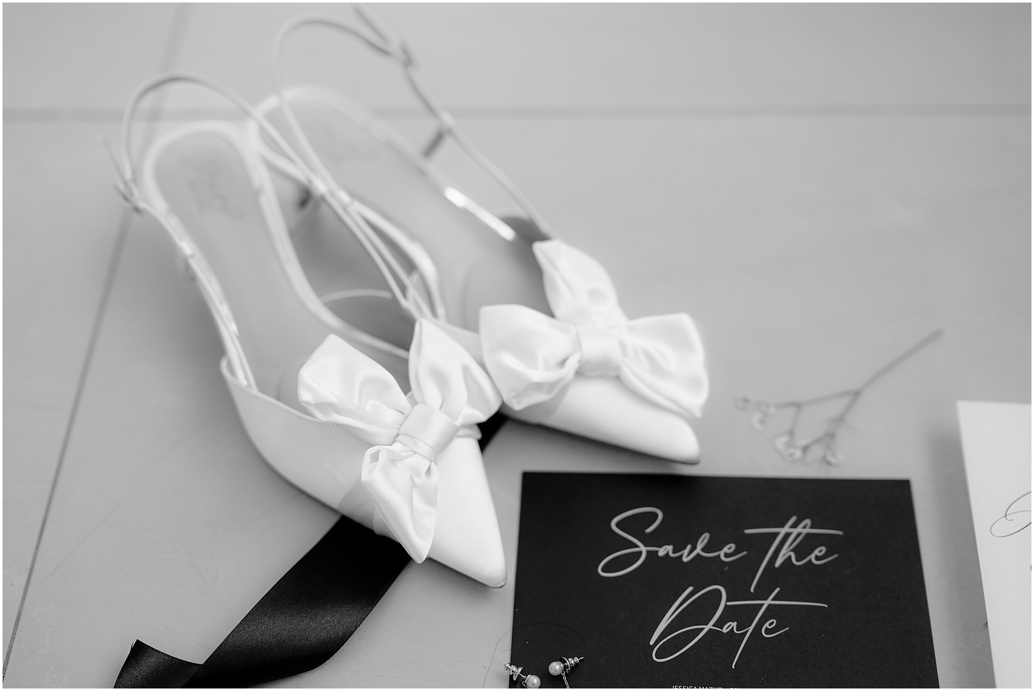 bride's white shoes with bows and black and white invitation suite 