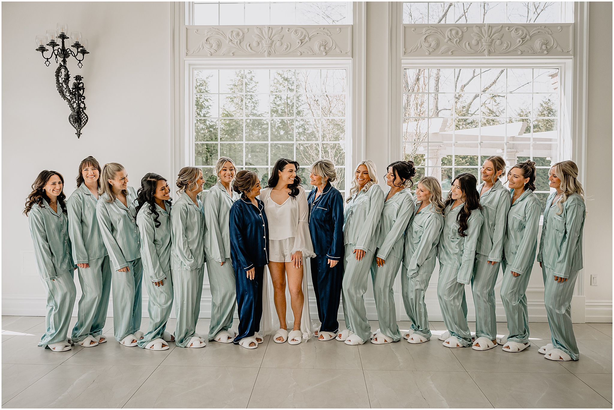 bride smiles with mothers and bridesmaids in matching pajamas inside suite at the Estate at Florentine Gardens