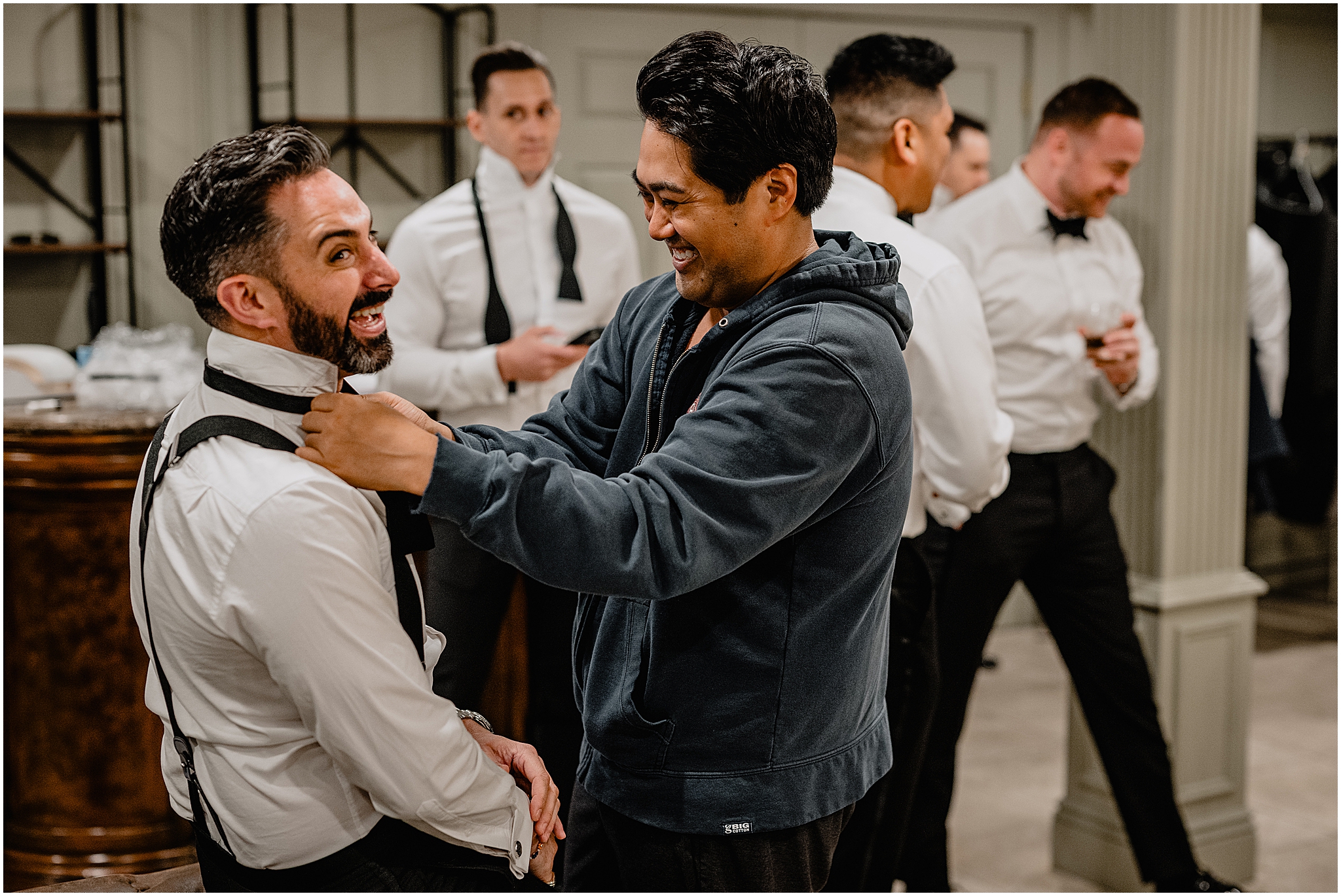 groom helps groomsman with bowtie during prep for NJ wedding