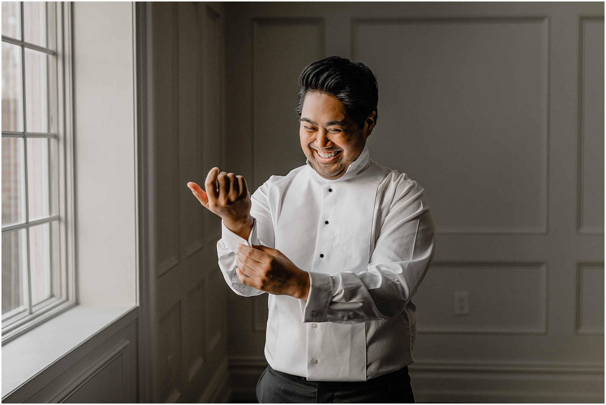 asian groom adjusts cufflinks in front of window at the Estate at Florentine Gardens
