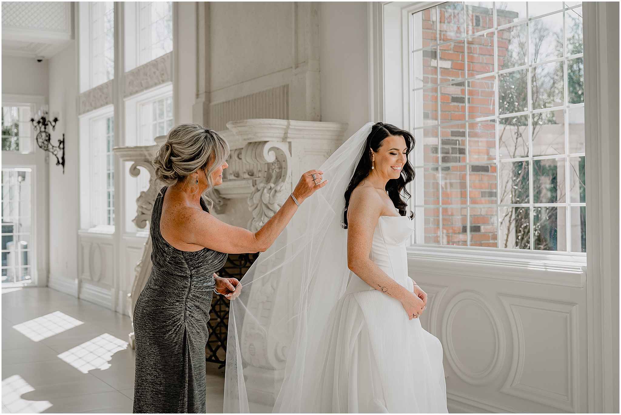 mother pulls veil behind bride during prep for wedding at the Estate at Florentine Gardens