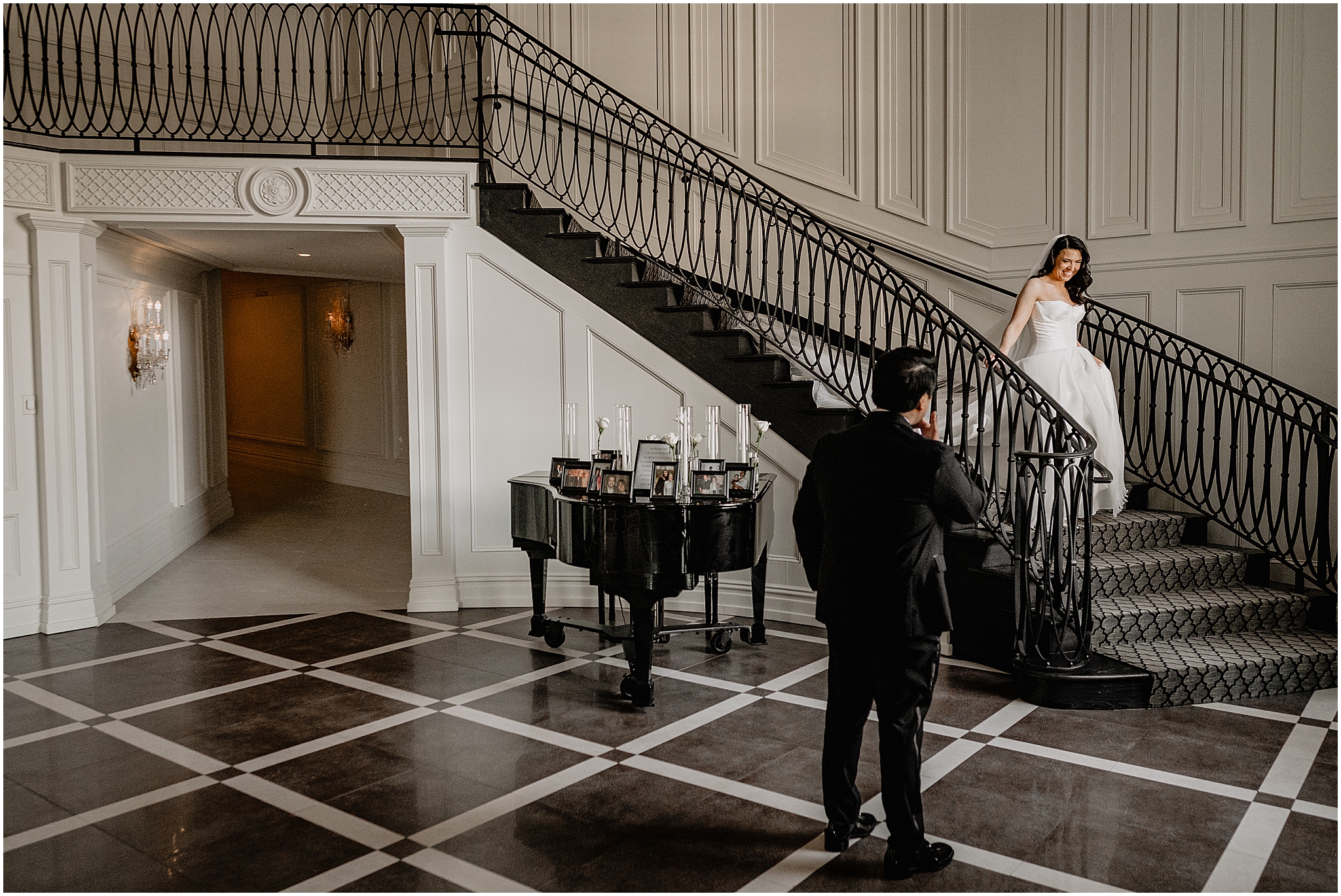 groom turns to look at bride walking down staircase inside the Estate at Florentine Gardens