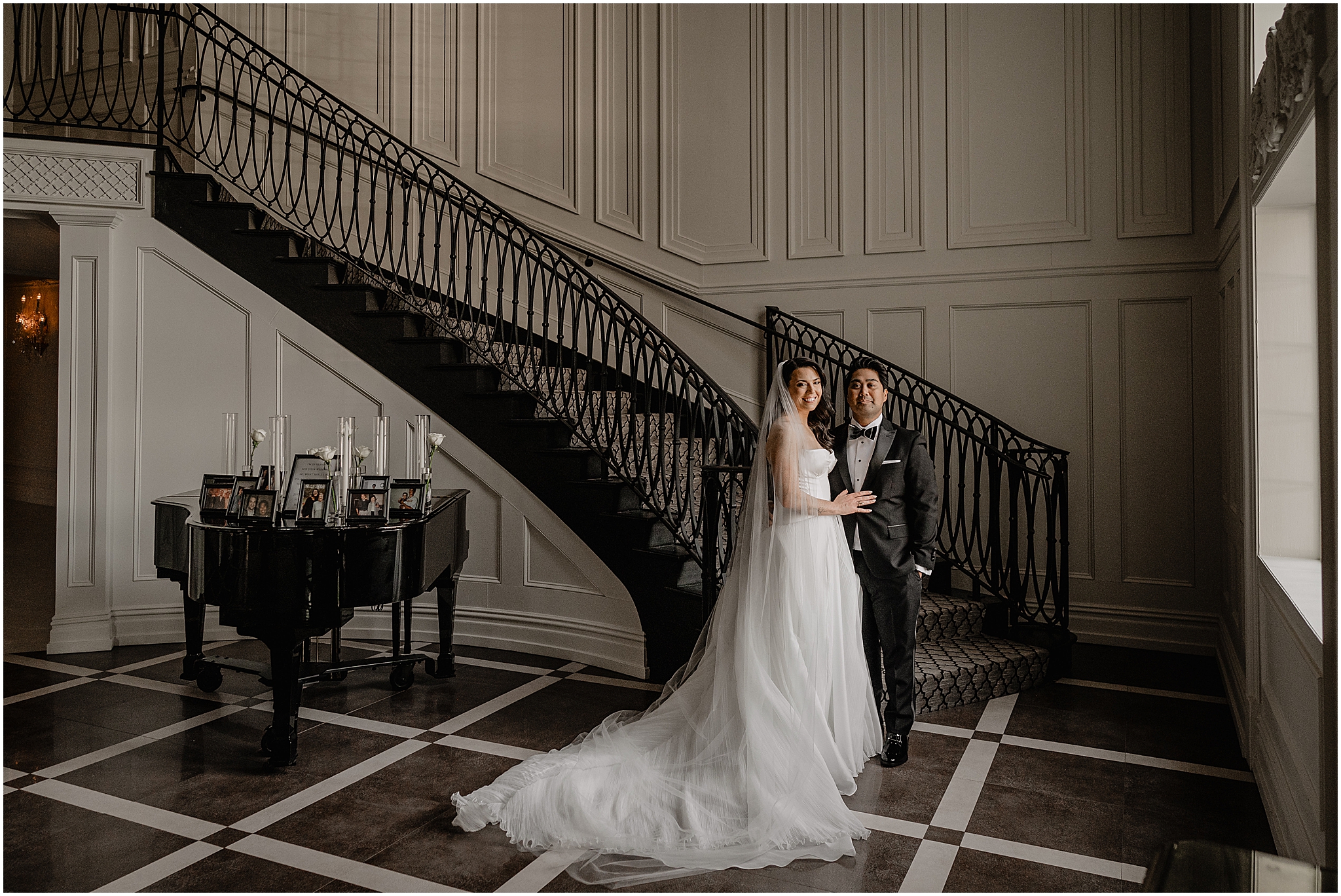 newlyweds hug by black staircase in lobby of the Estate at Florentine Gardens