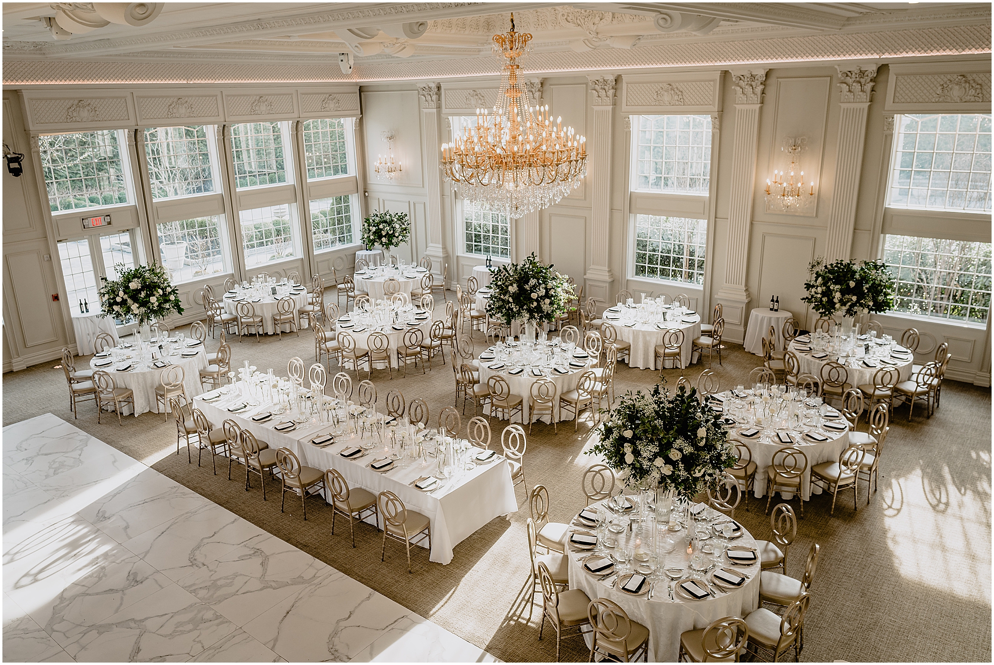 wedding reception in ballroom at the Estate at Florentine Gardens with gold chairs, white and green flowers, and place settings