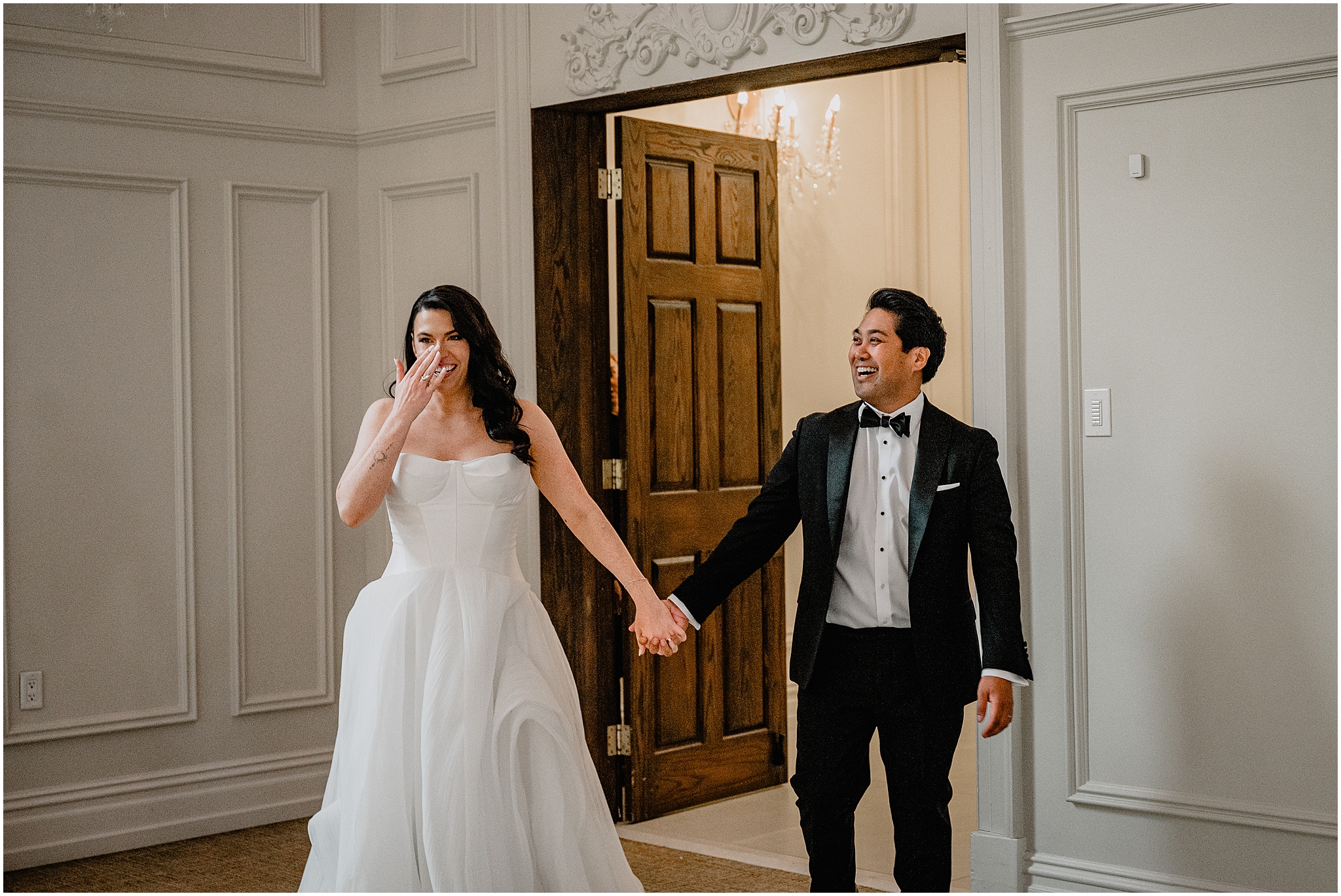 bride and groom grin holding hands walking into reception in New Jersey ballroom