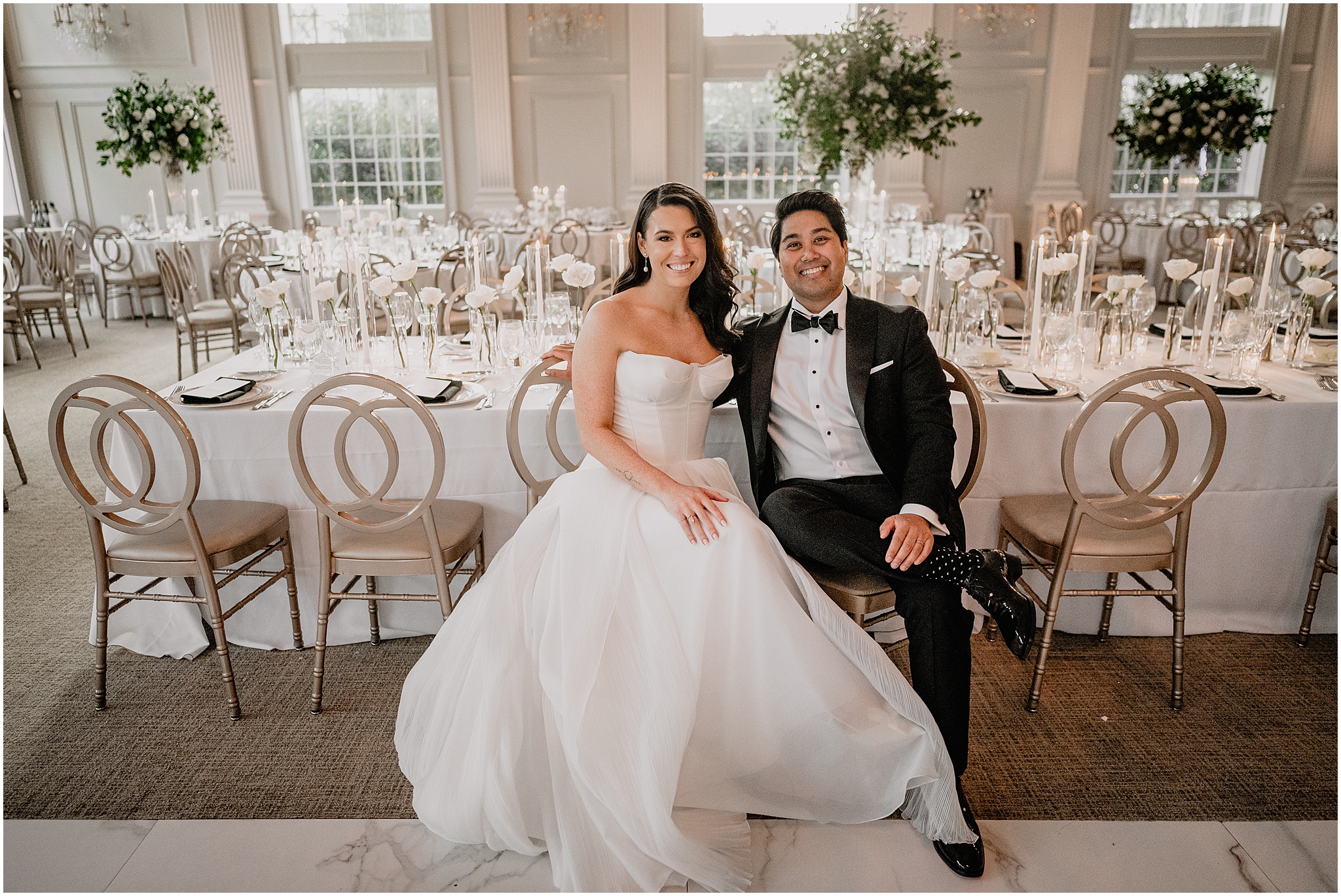 bride and groom sit by table during reception in the ballroom of the Estate at Florentine Gardens